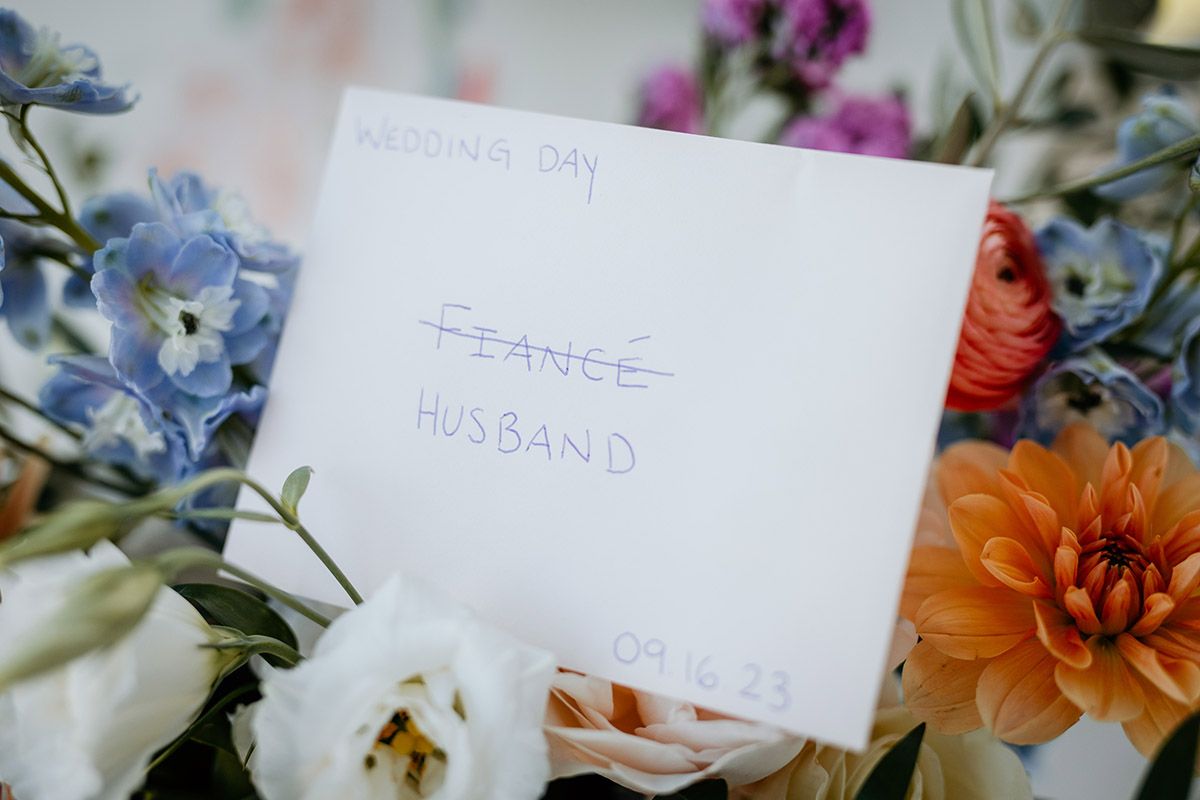 Place cards with handwritten names rest among delicate floral arrangements of blue and orange blooms at an elegant event.