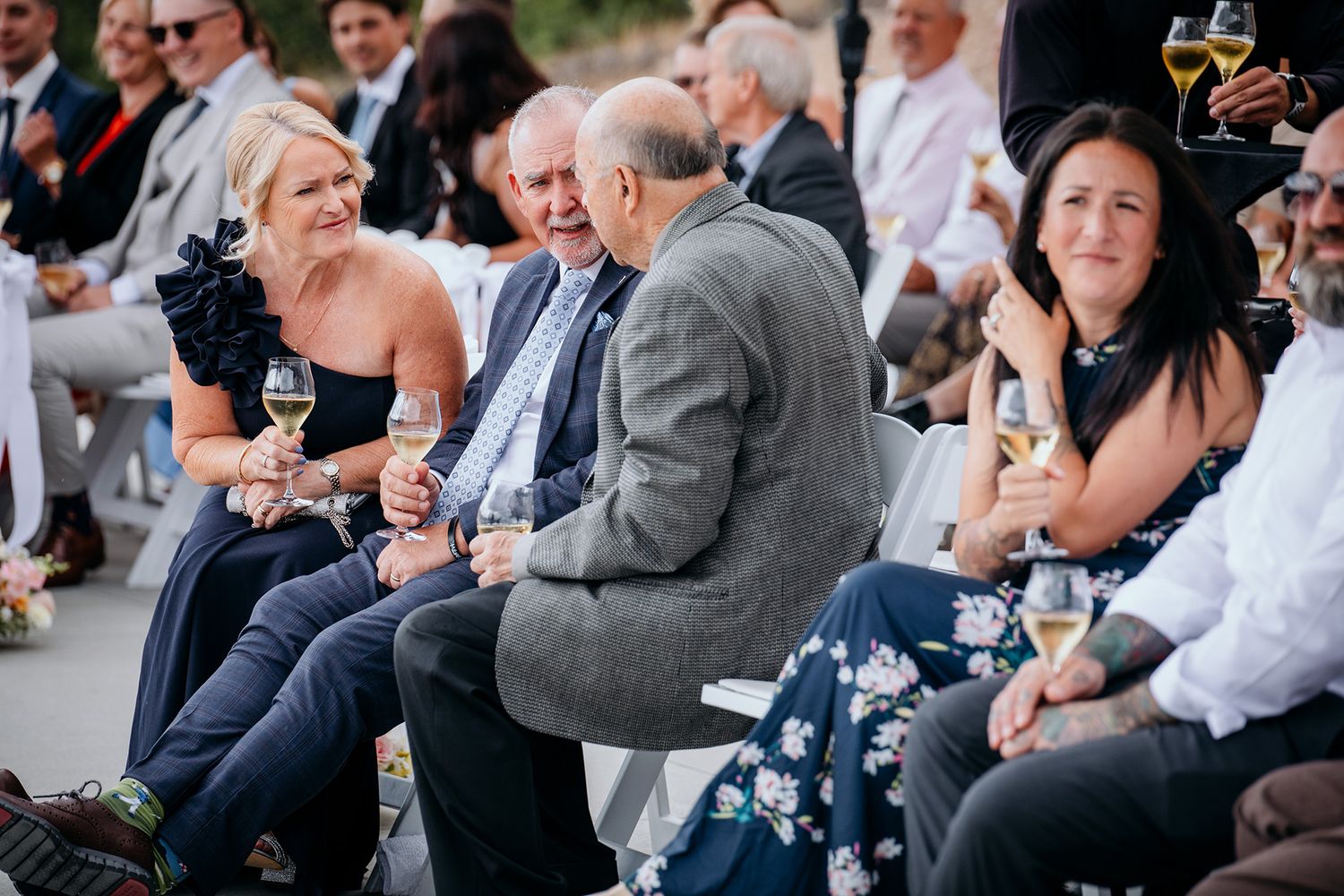 Wedding guests socialize and enjoy drinks during an outdoor reception gathering.