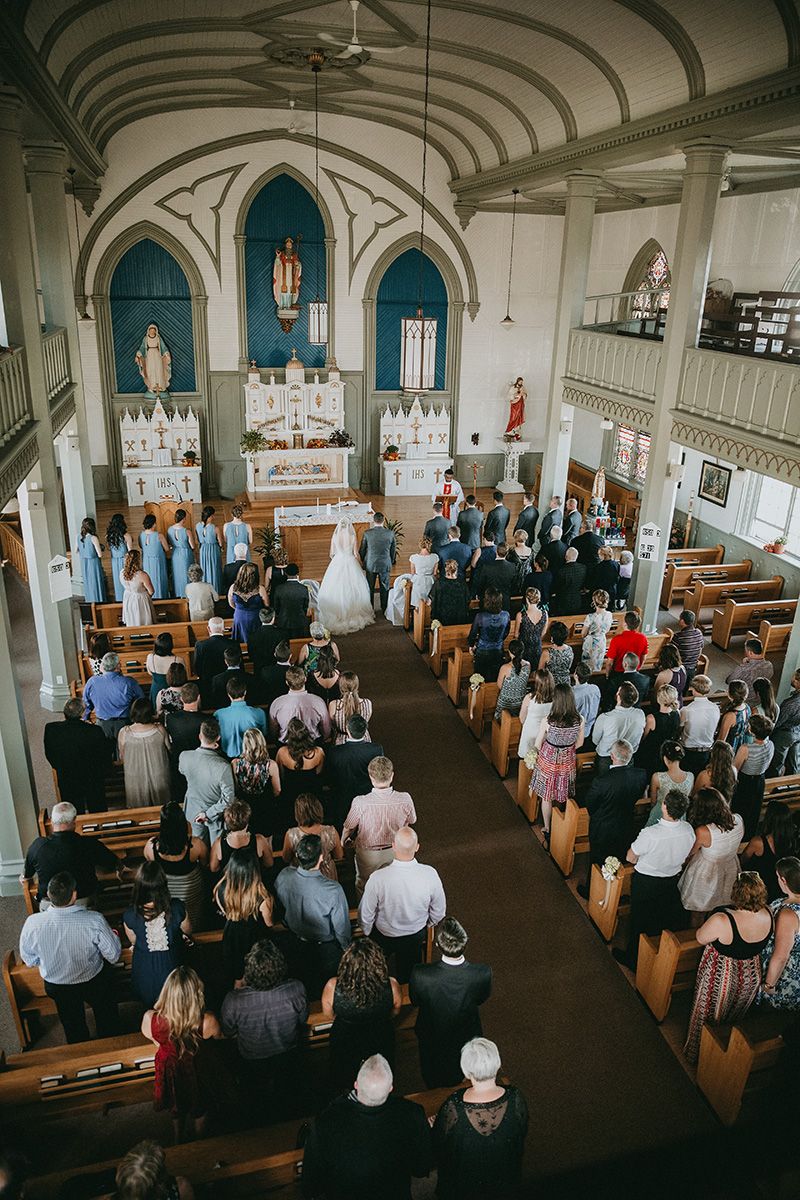 Wedding guests gather inside a traditional church sanctuary with ornate architecture and wooden pews during a ceremony.