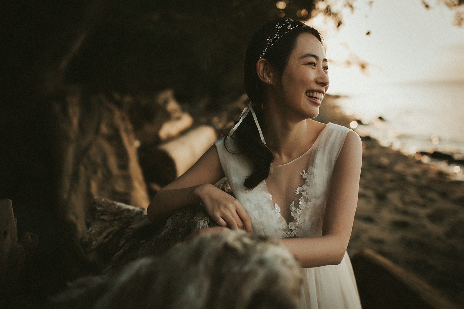 A joyful bride in a white dress laughs during a sunset photo shoot at Vancouver's Spanish Banks beach.