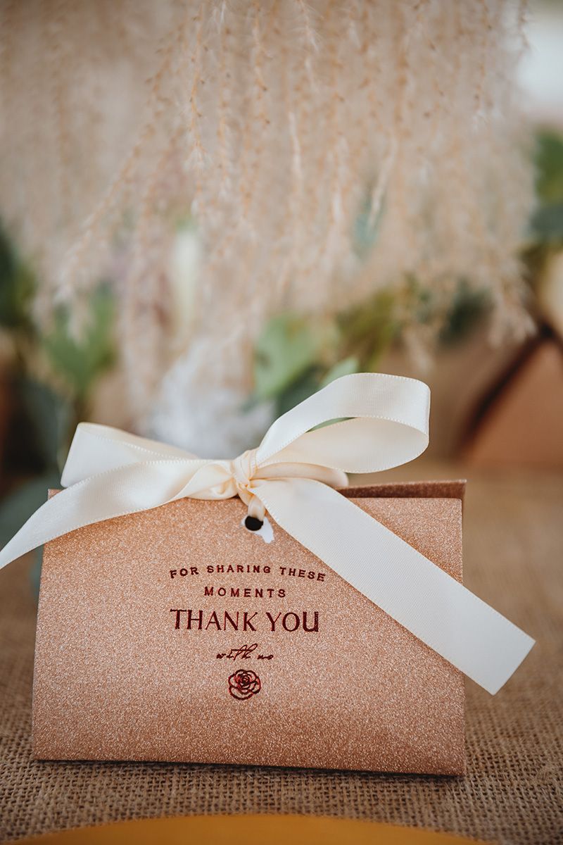 Close-up of brown kraft paper thank you cards with white ribbons arranged on burlap texture.