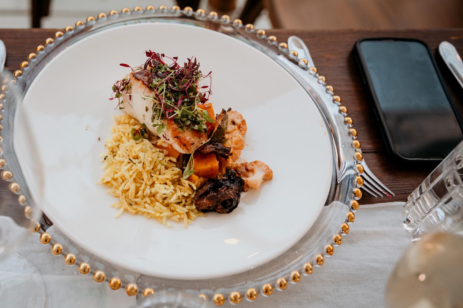 Plated dishes with garnishes on white plates with decorative beaded rims served at Vows and Vines Vineyard wedding.