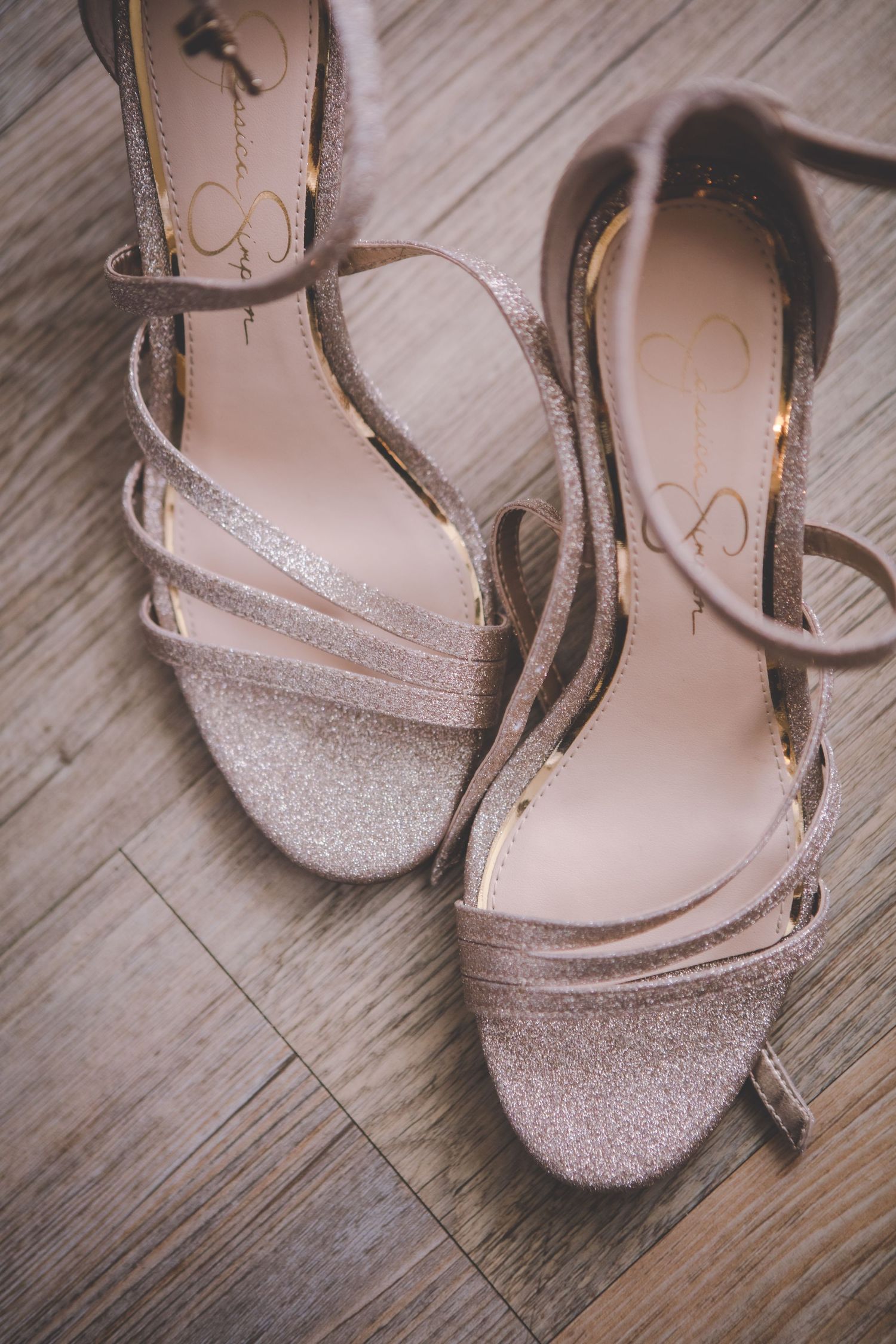 Sparkling silver wedding heels on wooden floor.