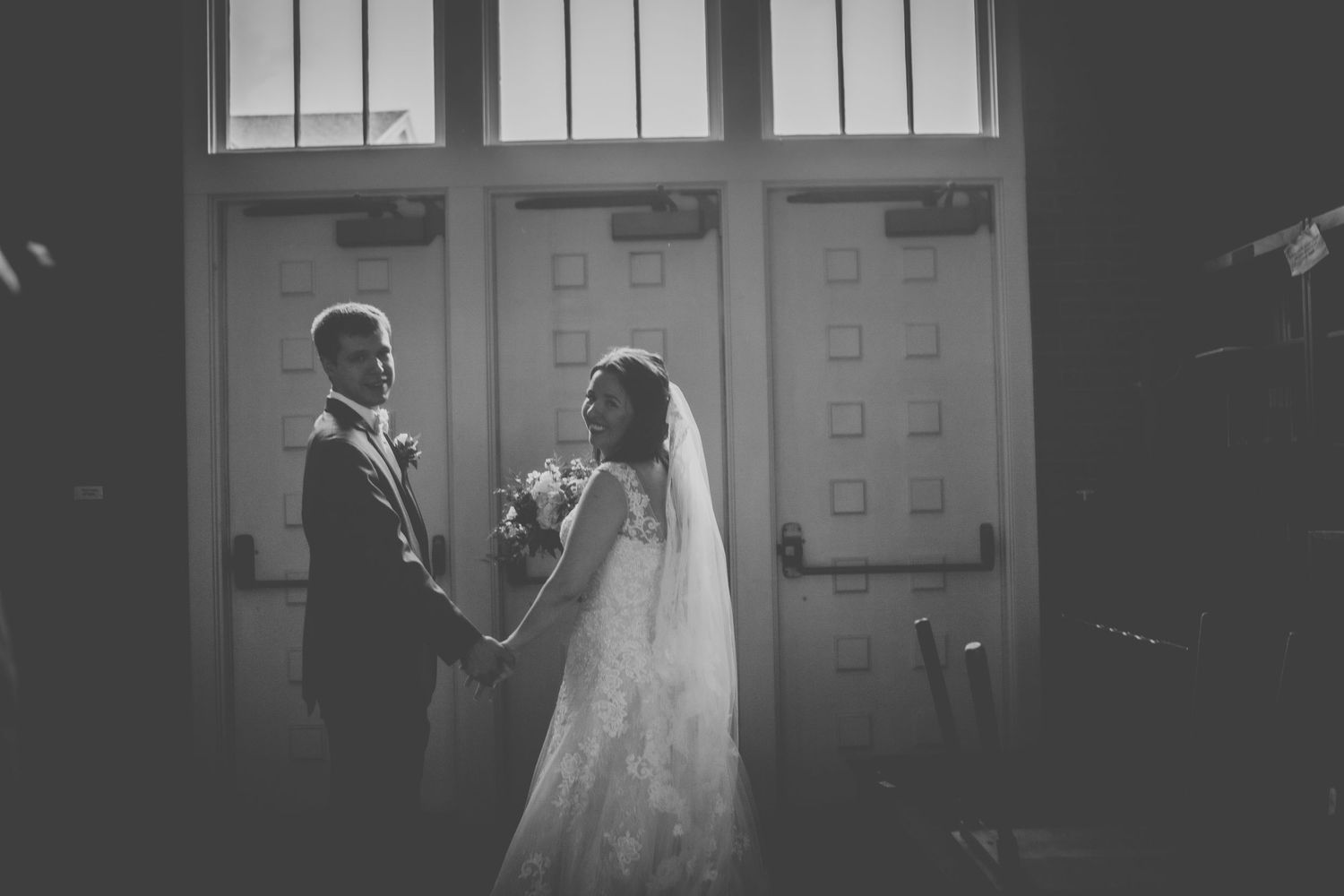 A silhouetted couple shares a romantic moment in front of church doors during their wedding ceremony.