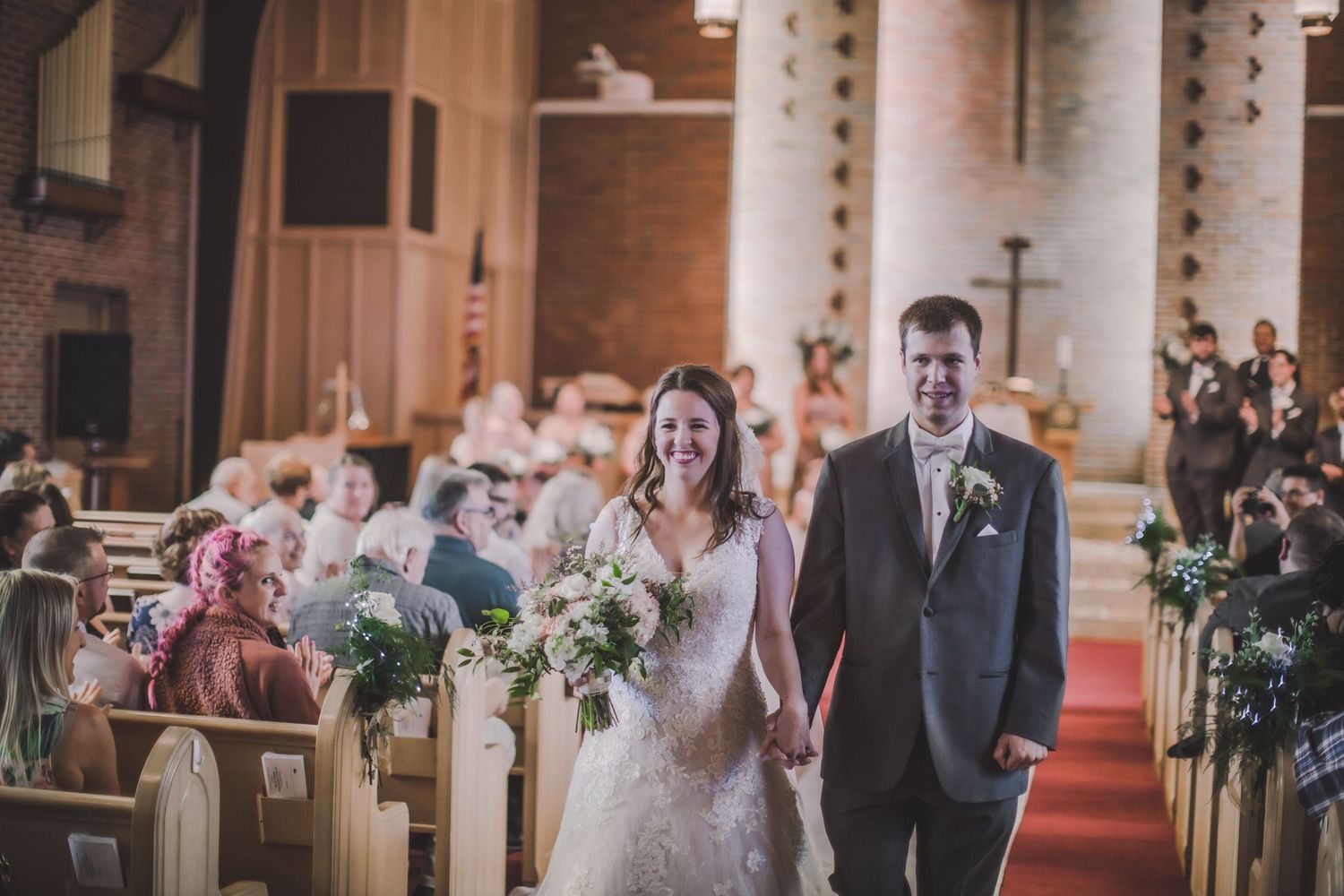 Wedding ceremony in progress inside historic church with ornate architectural details and stained glass windows.