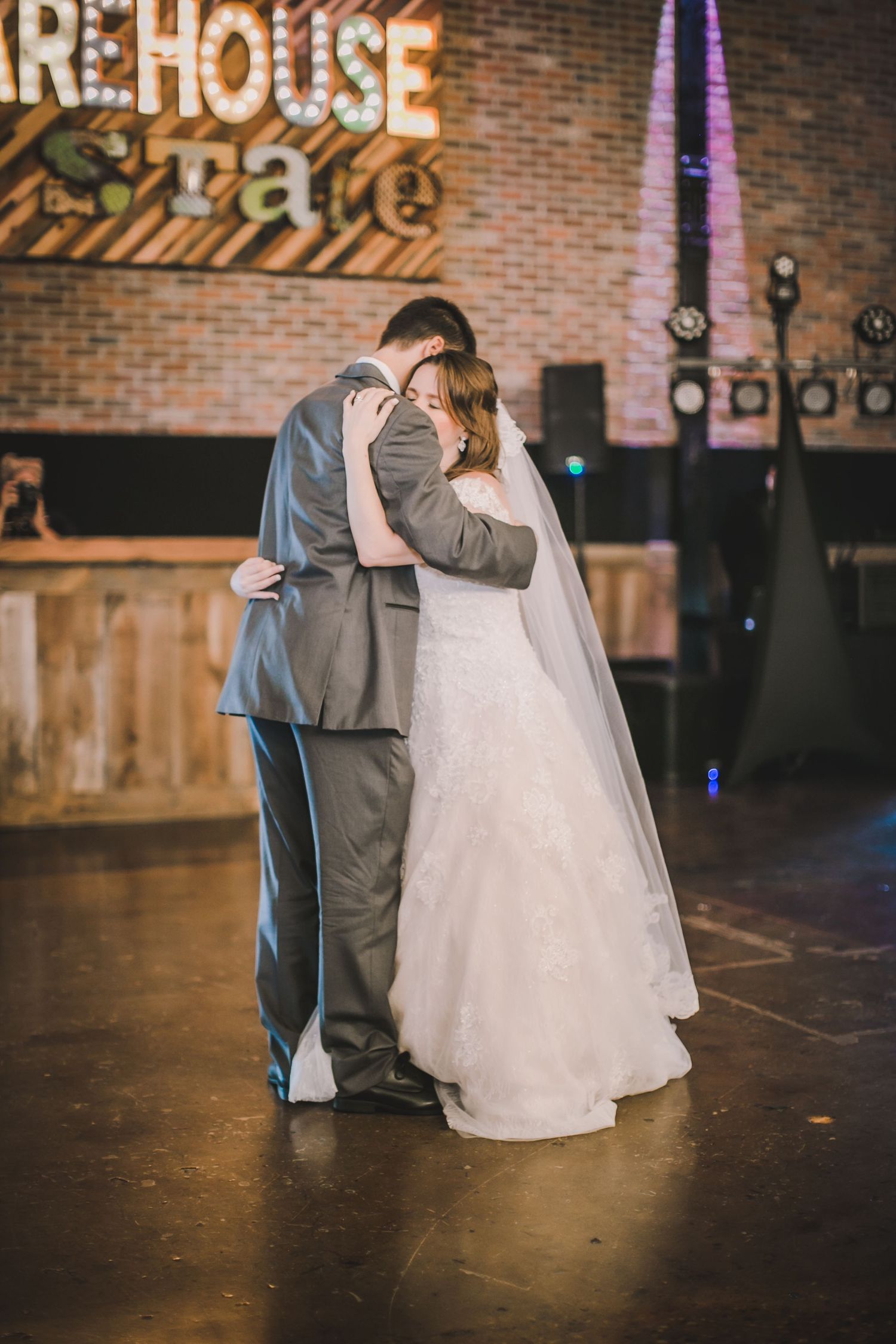 A couple dances together in an intimate moment on their wedding day in a rustic venue.