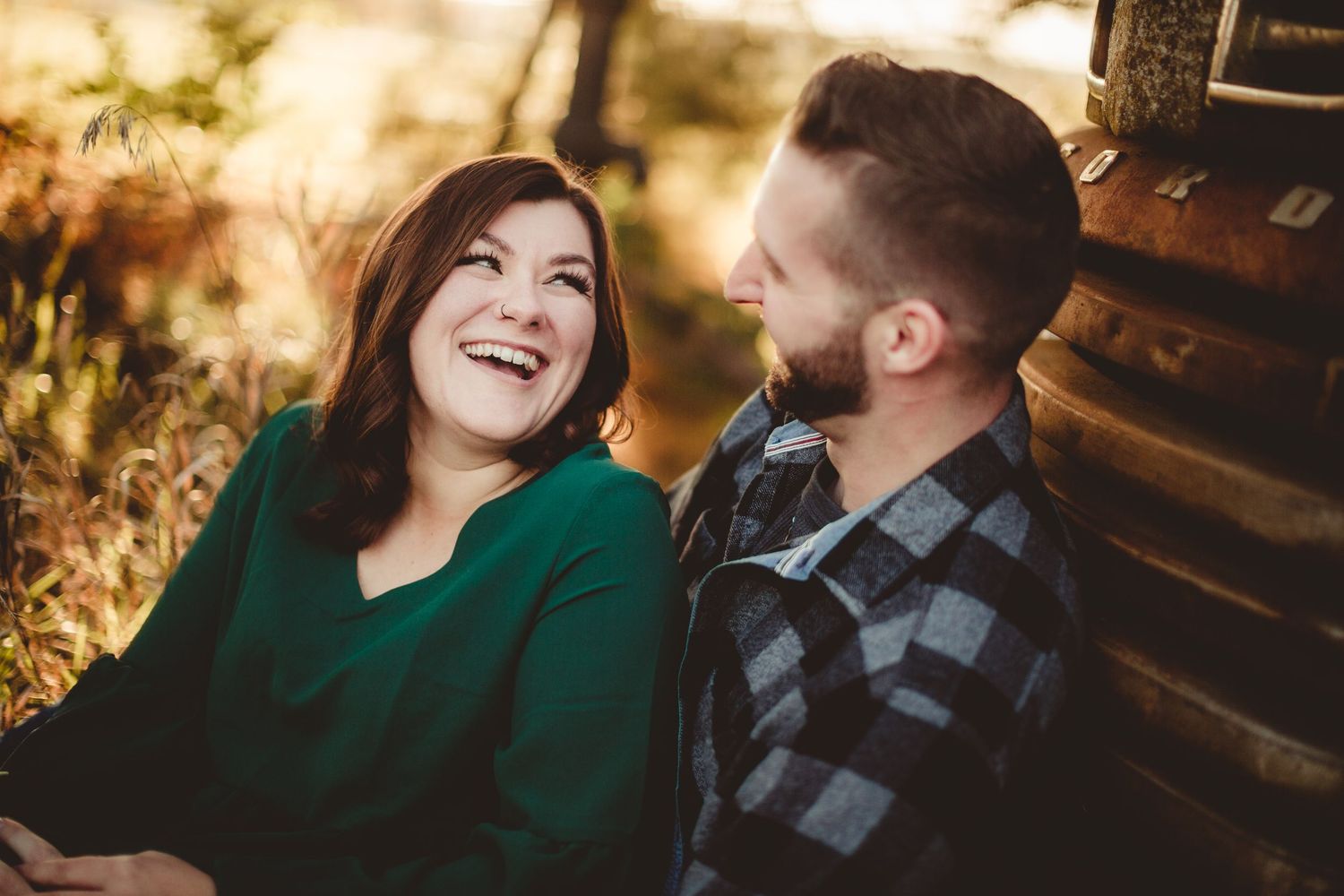 Joyful moment shared between couple sitting by rustic truck during golden hour.