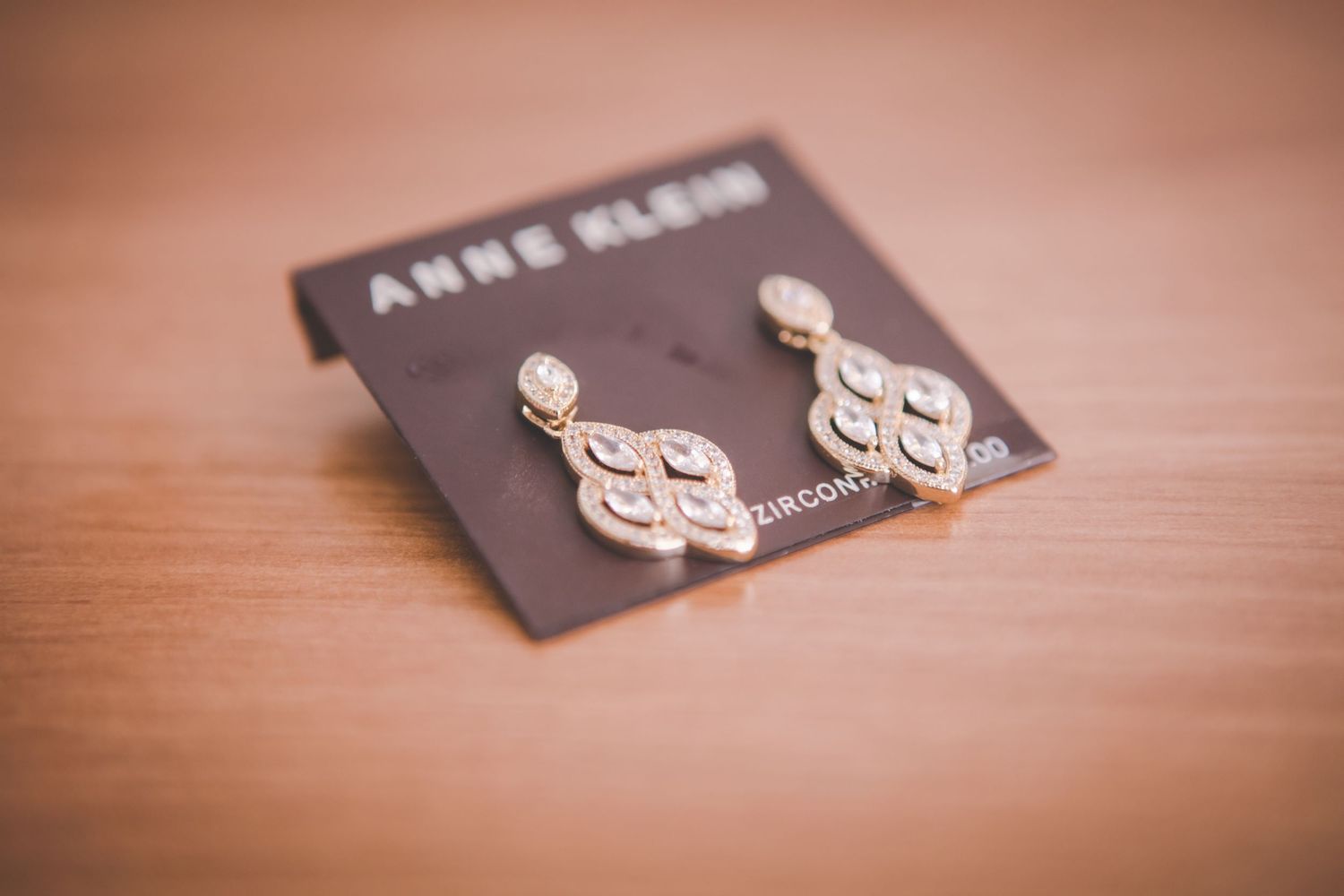 Elegant silver teardrop-shaped earrings with crystal accents displayed on a brown Anne Klein card.