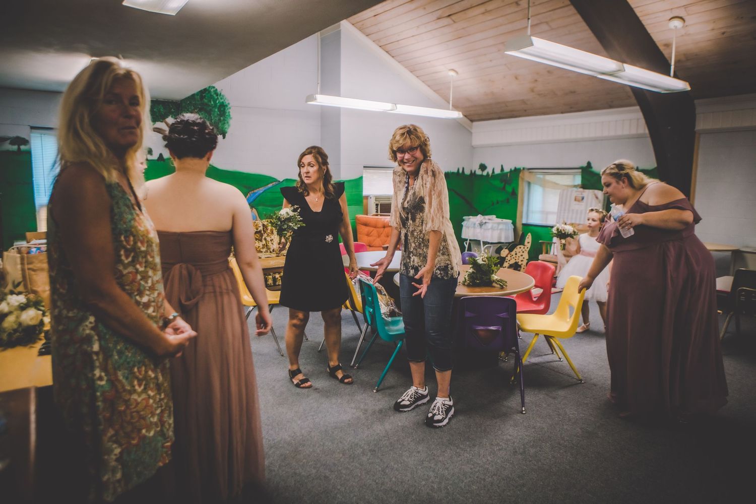 Wedding party gathers in casual moment before ceremony in room with wood ceiling and green accents.