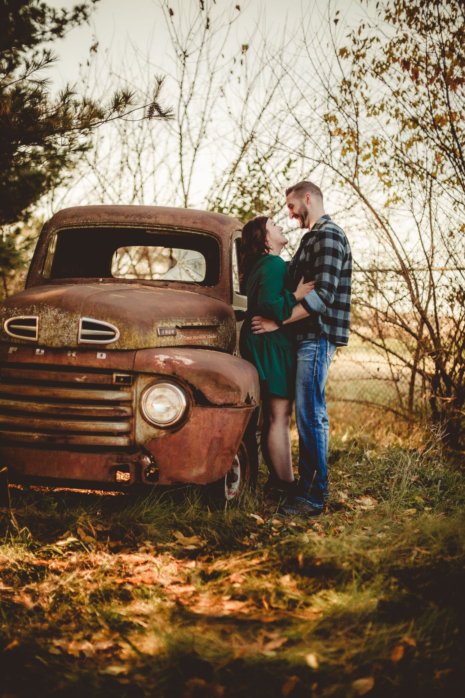 A vintage rusty Ford truck provides a rustic backdrop for a romantic autumn photoshoot during golden hour.