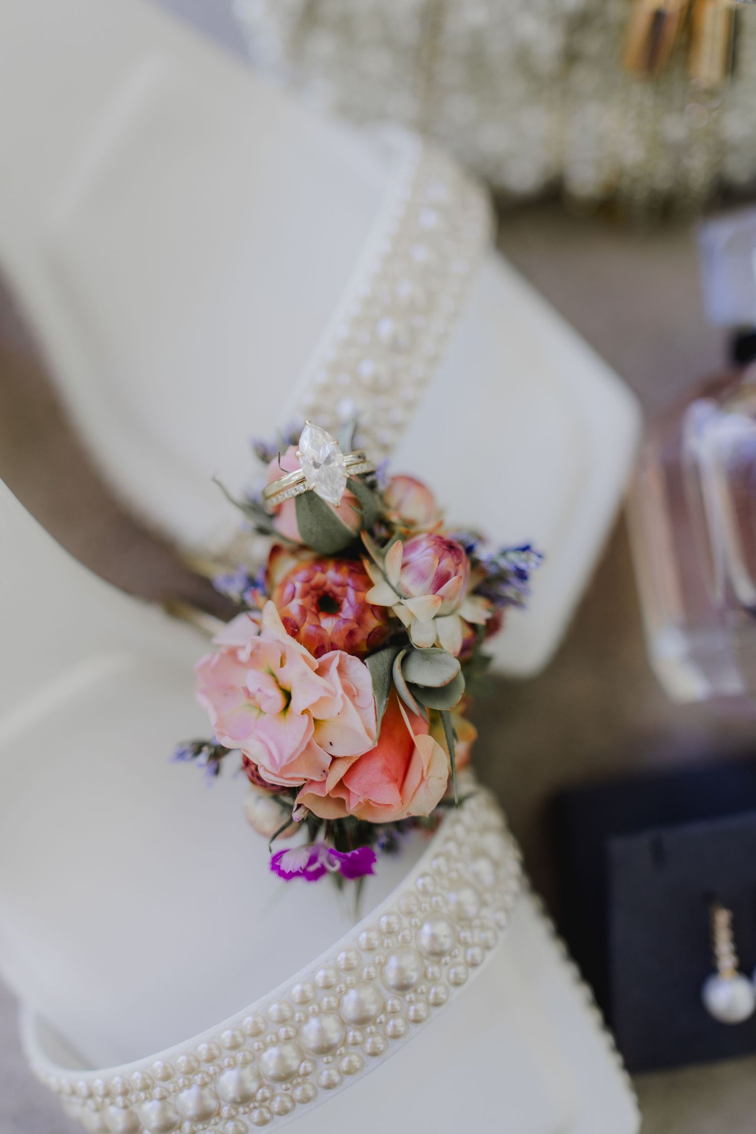 Elegant white wedding cake with pearl trim and colorful pink floral arrangement decoration.