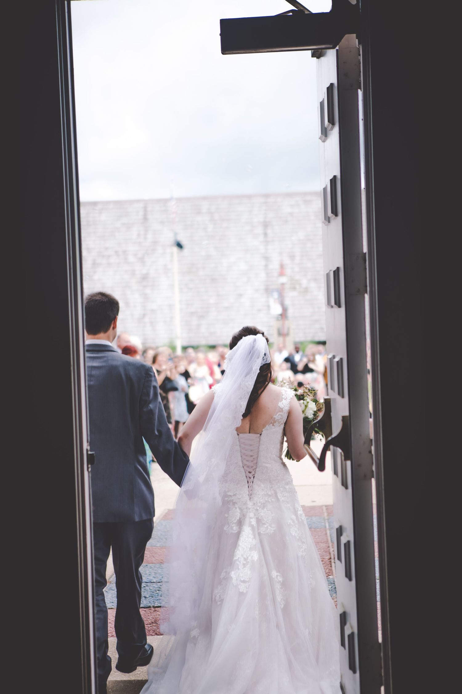 View through doorway of a bride in white gown exiting the church after ceremony.