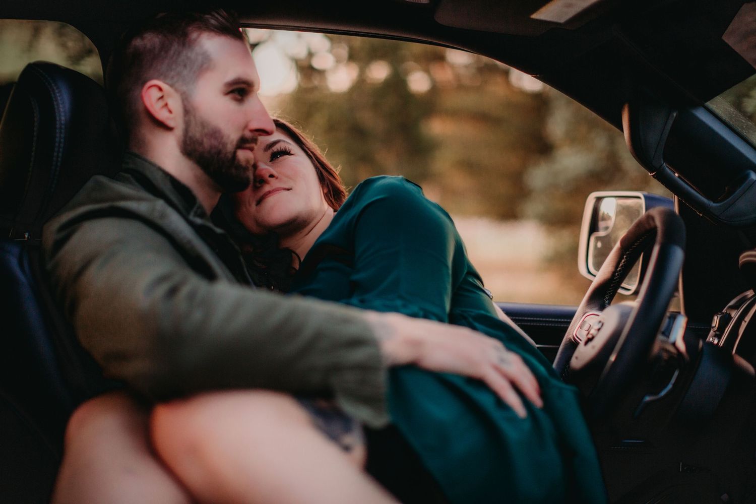 Intimate couple sharing a romantic moment while sitting in a car during golden hour.