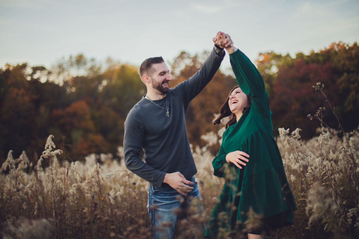 A couple embraces tenderly among tall grasses during a fall outdoor photoshoot.