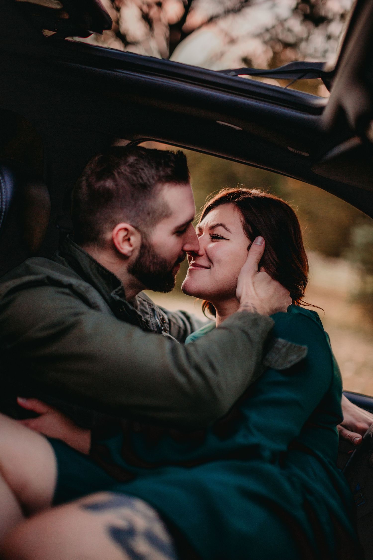 Tender caress and intimate moment captured in car during golden hour.