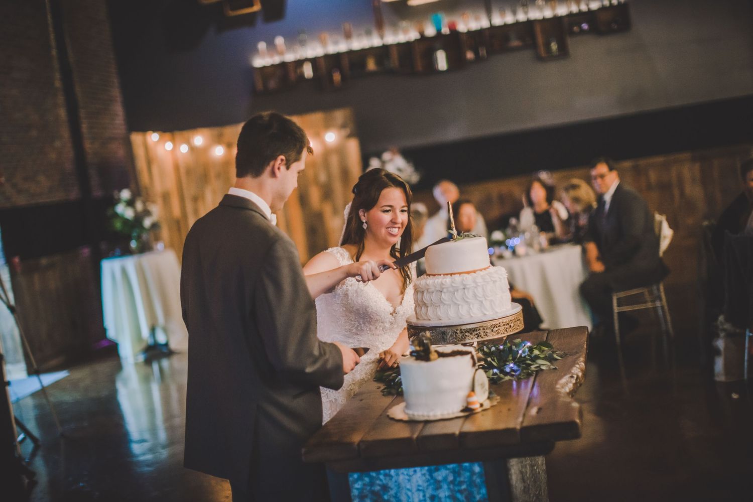 Wedding reception scene with string lights and rustic decor at industrial venue.
