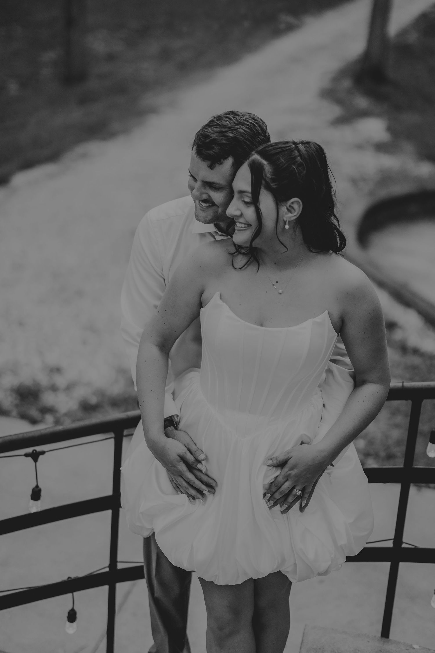 Happy couple embraces on a balcony in black and white engagement photo.