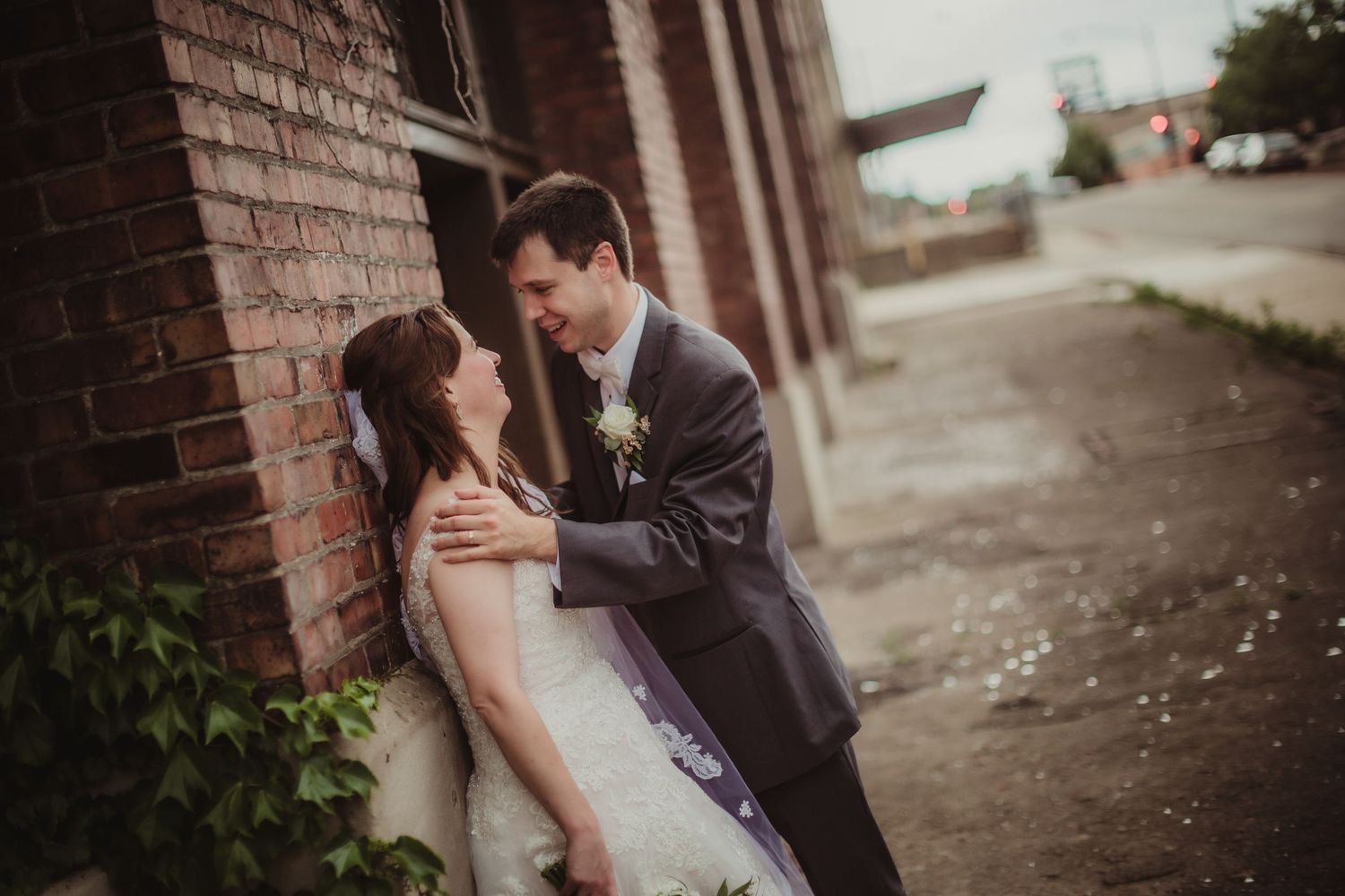 Romantic wedding portrait against a rustic brick wall in an urban setting.