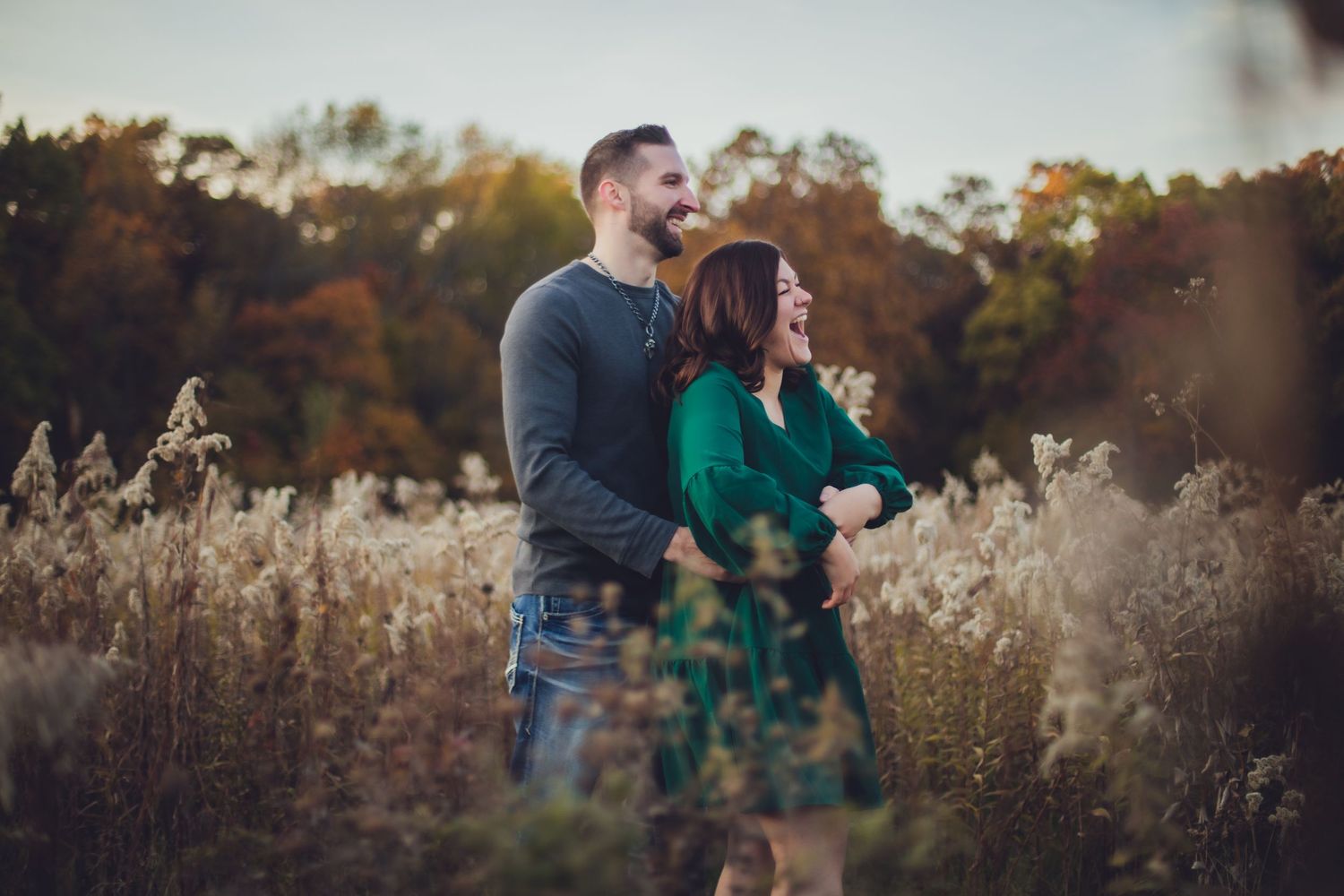 Couple enjoying a playful moment together in a fall field with golden light.