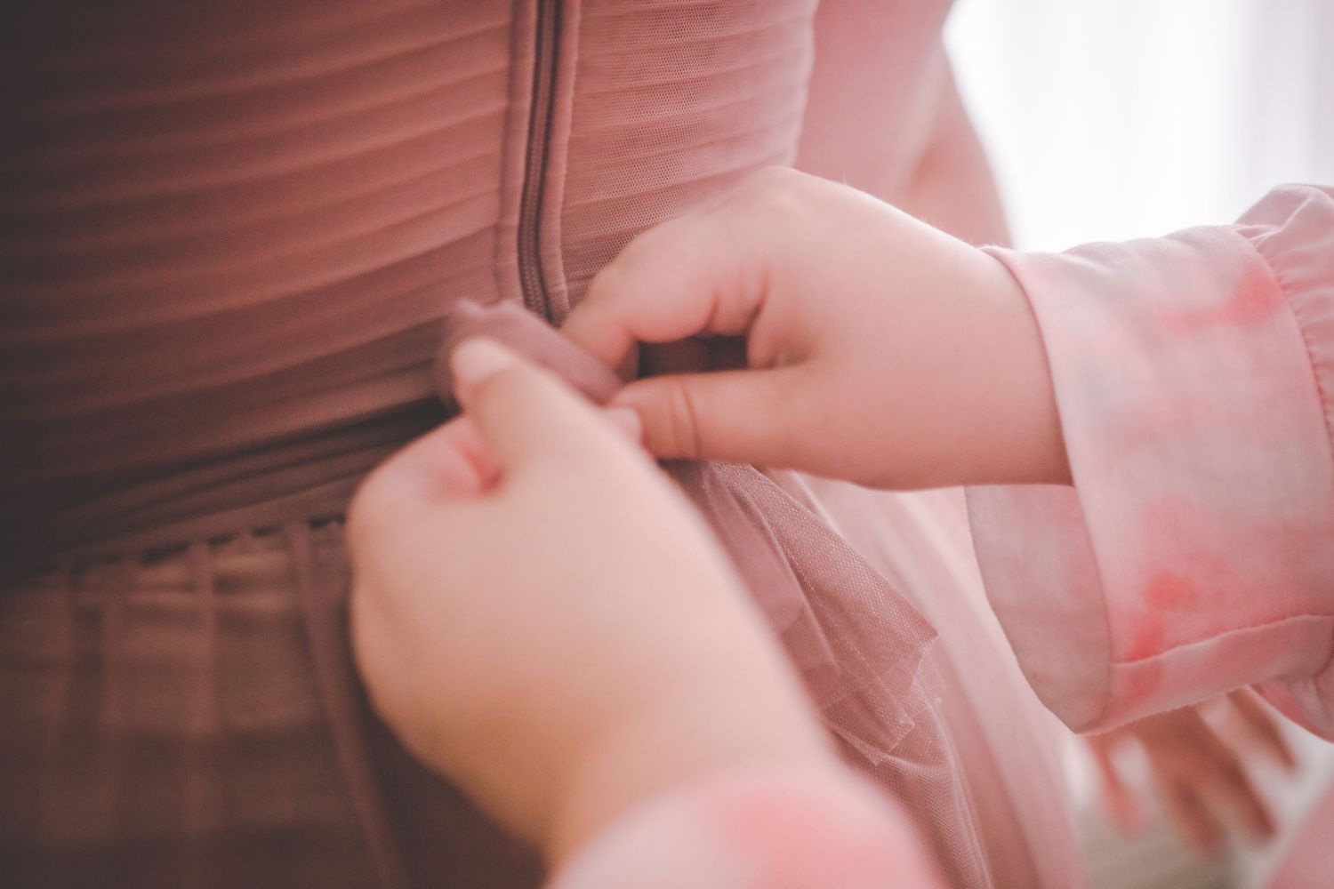 Delicate pink fabric and ribbons of a wedding dress in natural light.