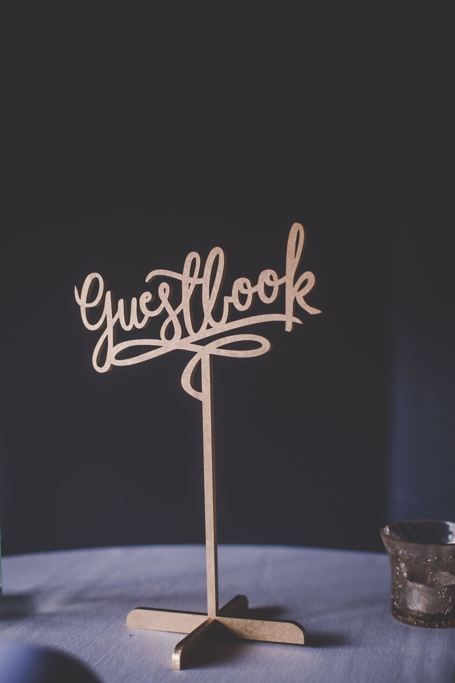 Wooden wedding table decorations with cursive text signs against a dark background.