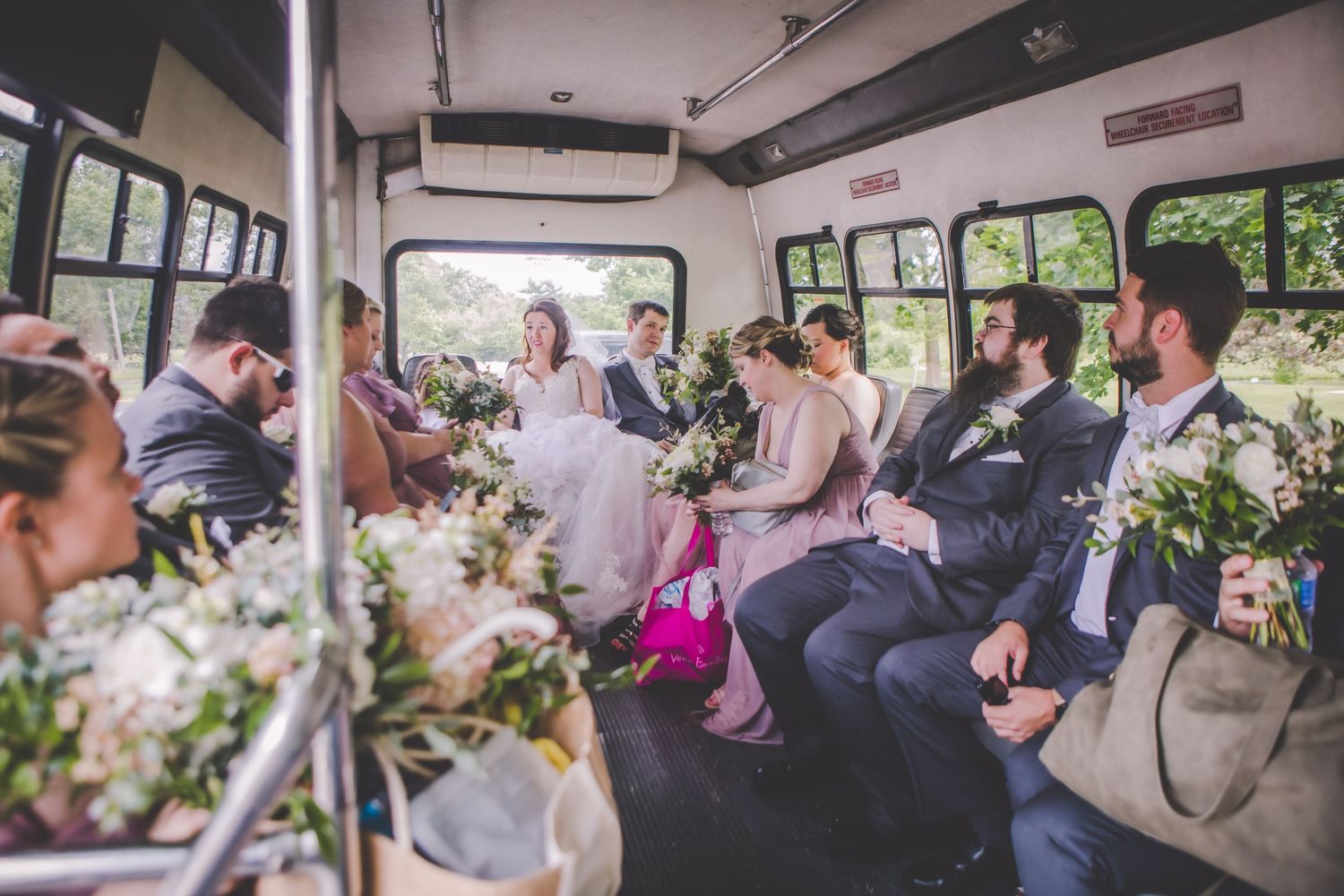 Interior view of wedding party seated inside decorated shuttle bus.