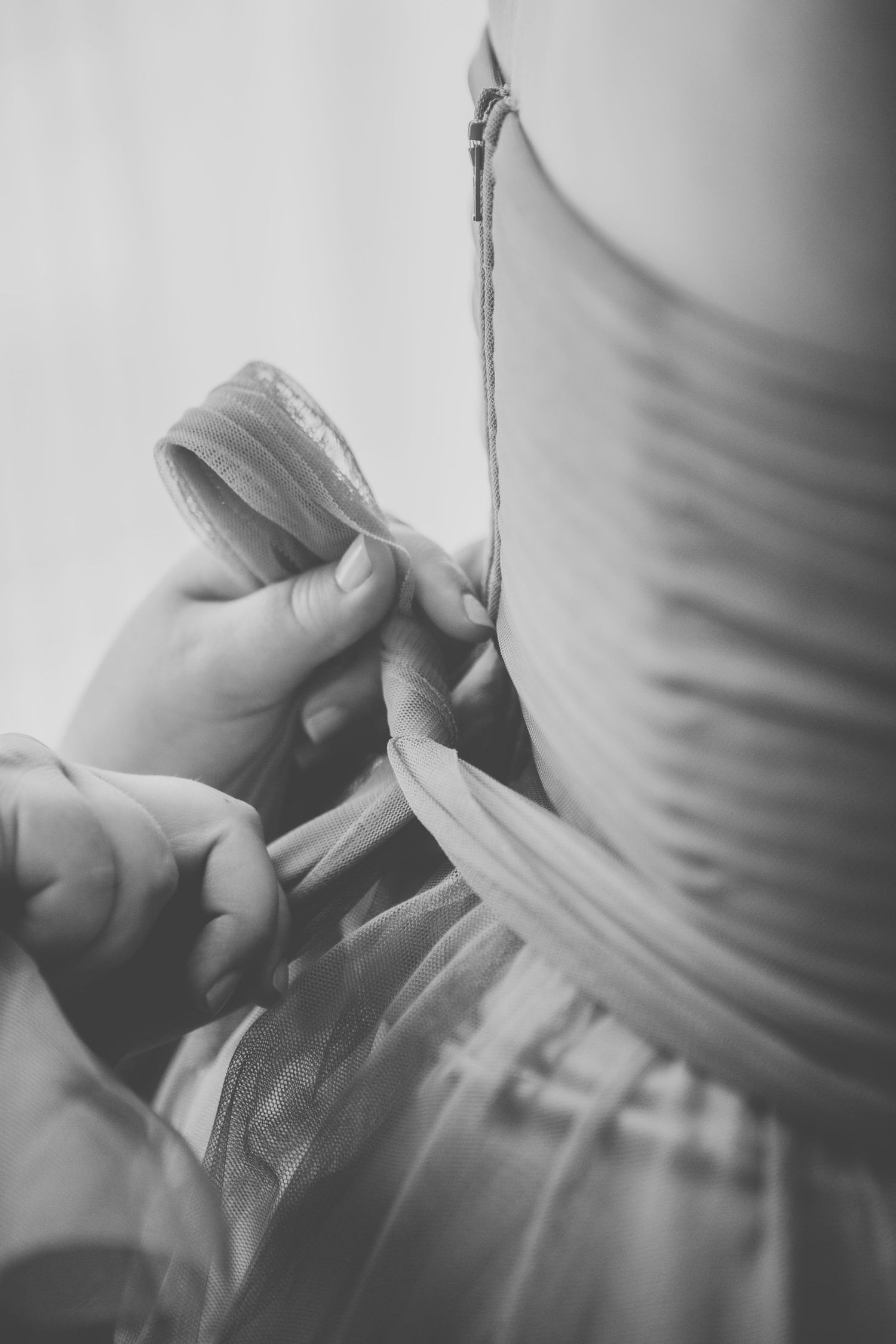Black and white image of hands adjusting or fastening details on a wedding dress.