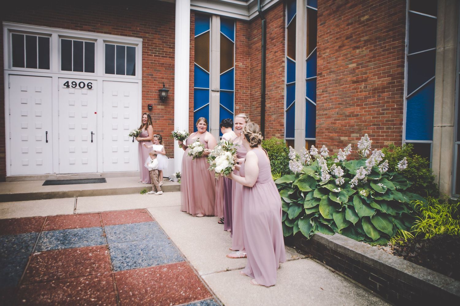 Wedding party members in pink dresses standing outside brick building.