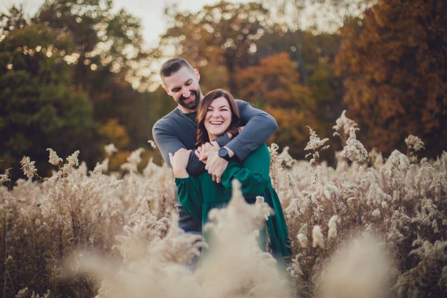 Playful couple shares candid moment in field during fall photo session.
