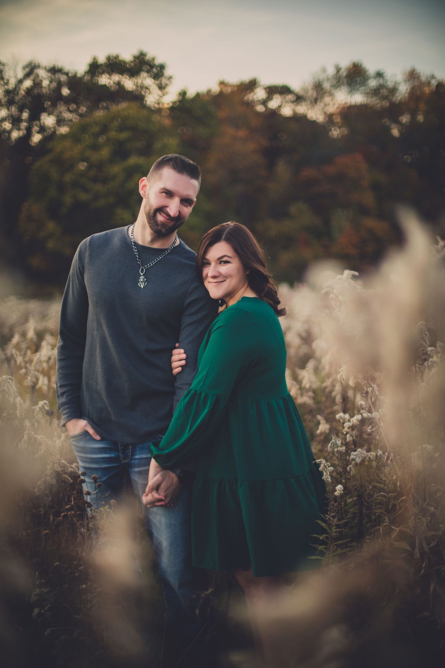 A couple enjoying a tender moment together in a field of dried grass during autumn.