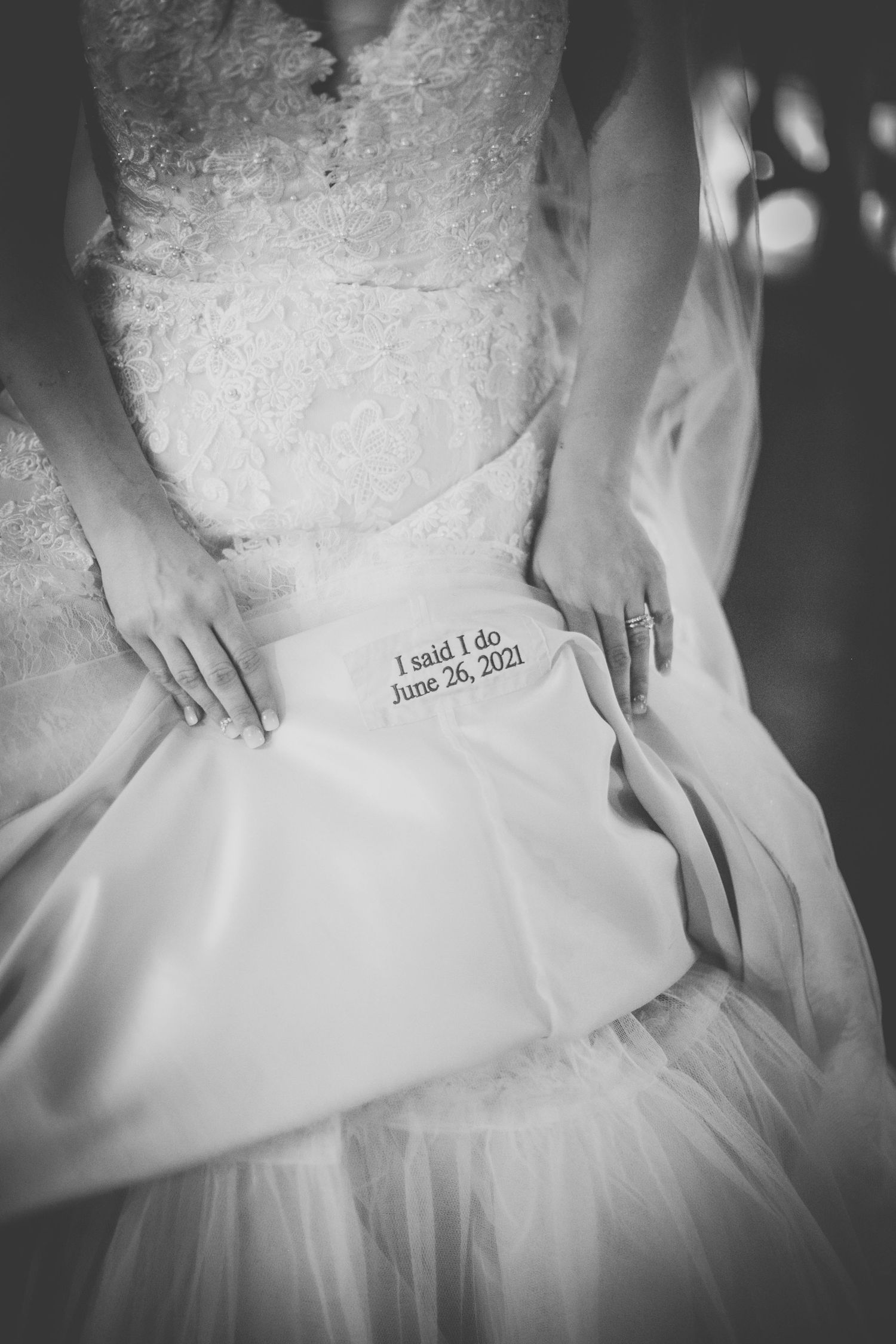 Close-up detail of a wedding dress showing embroidered text 'I said I do' and 'June 26 2021' in blue thread.