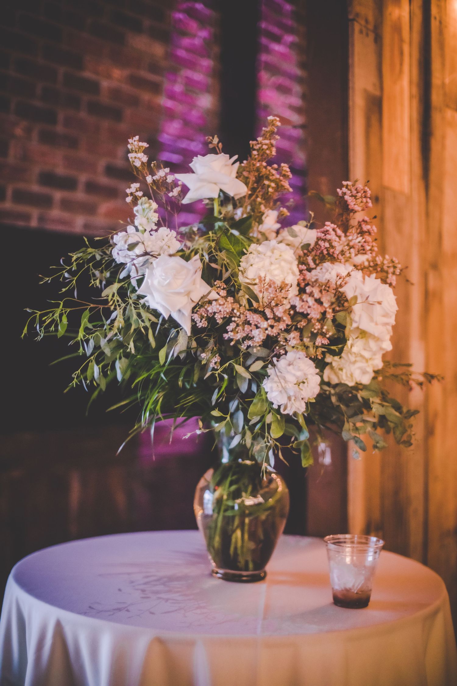 Elegant floral centerpiece with white and pink blooms in glass vase on round table.