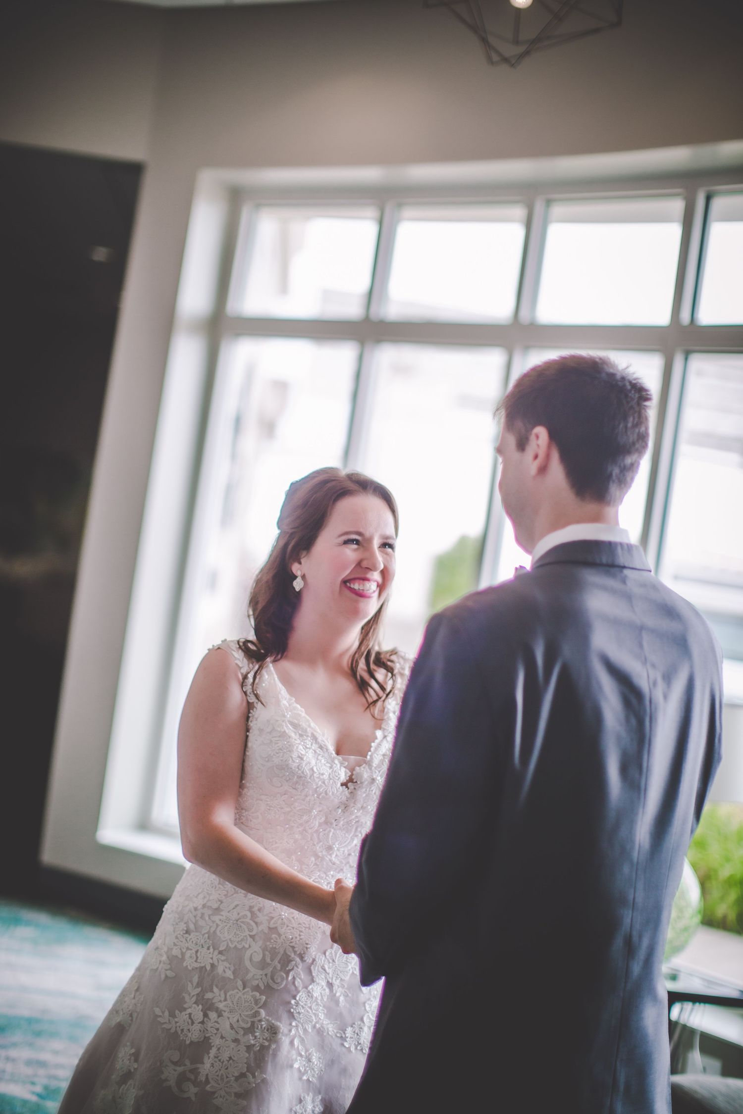 A sweet moment shared between a couple in wedding attire near floor-to-ceiling windows.