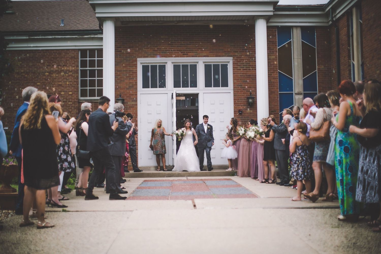 Church exterior with wedding guests forming receiving line after ceremony.