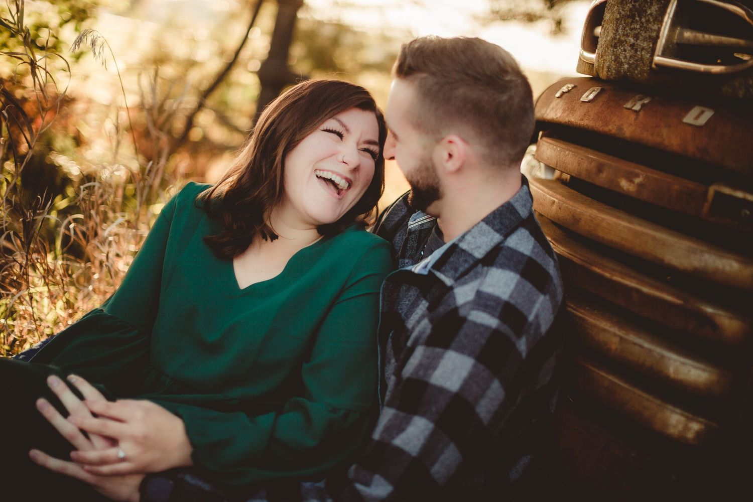 Happy couple sharing joyful moment against wooden cabin wall at sunset.