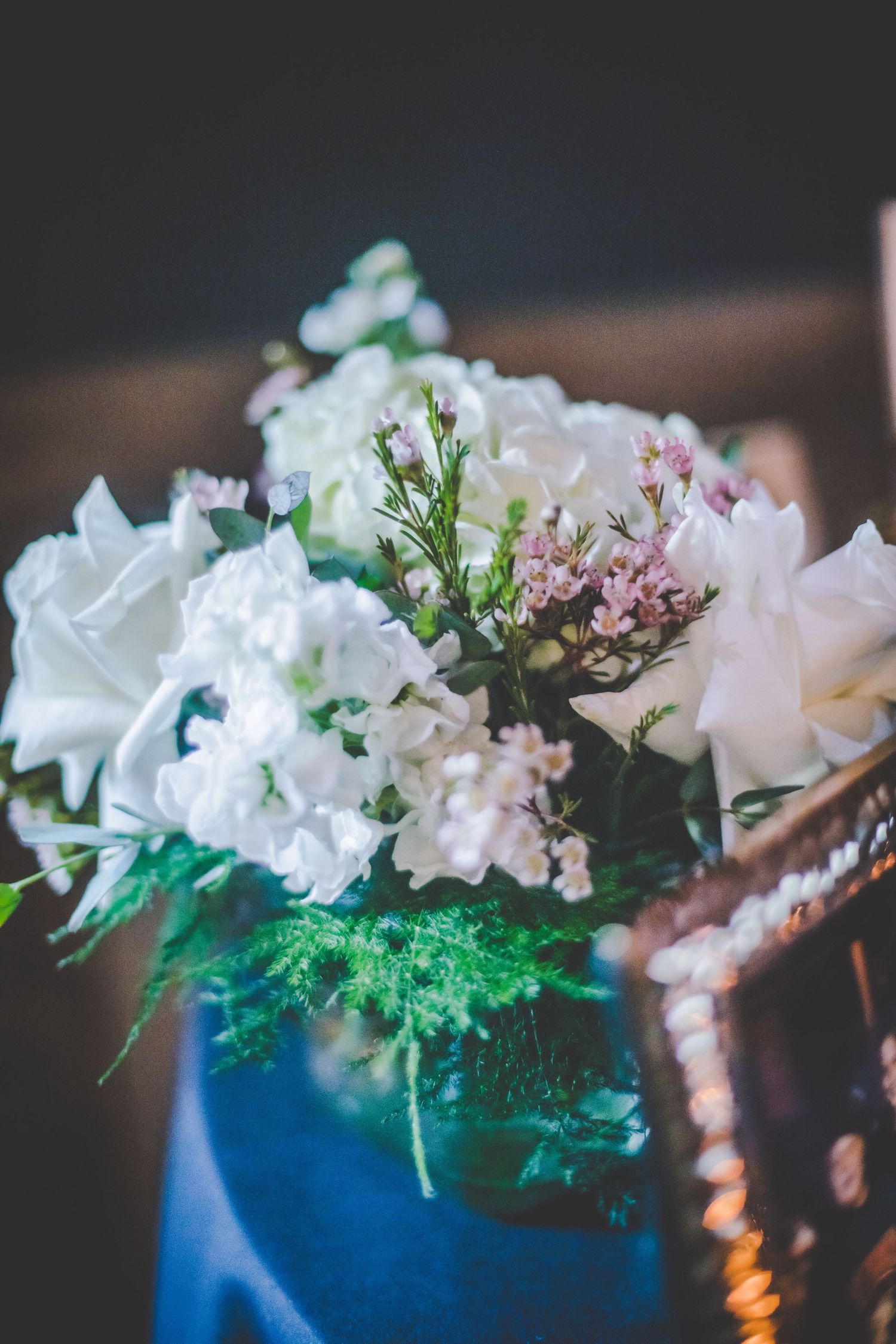 A delicate floral arrangement featuring white flowers and greenery in soft focus.