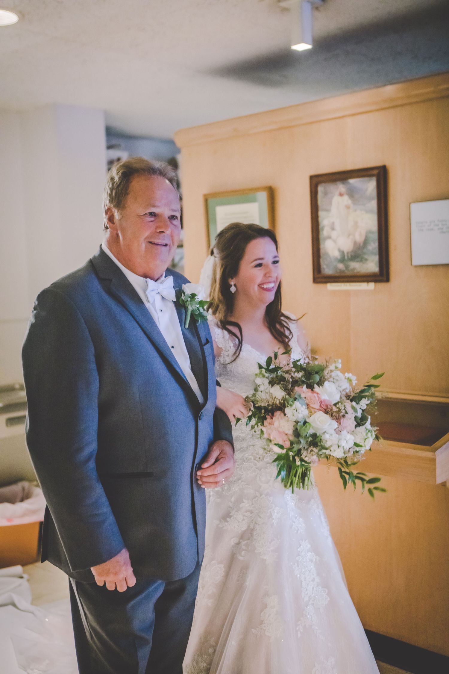 Wedding party walking down a church hallway with floral bouquets.