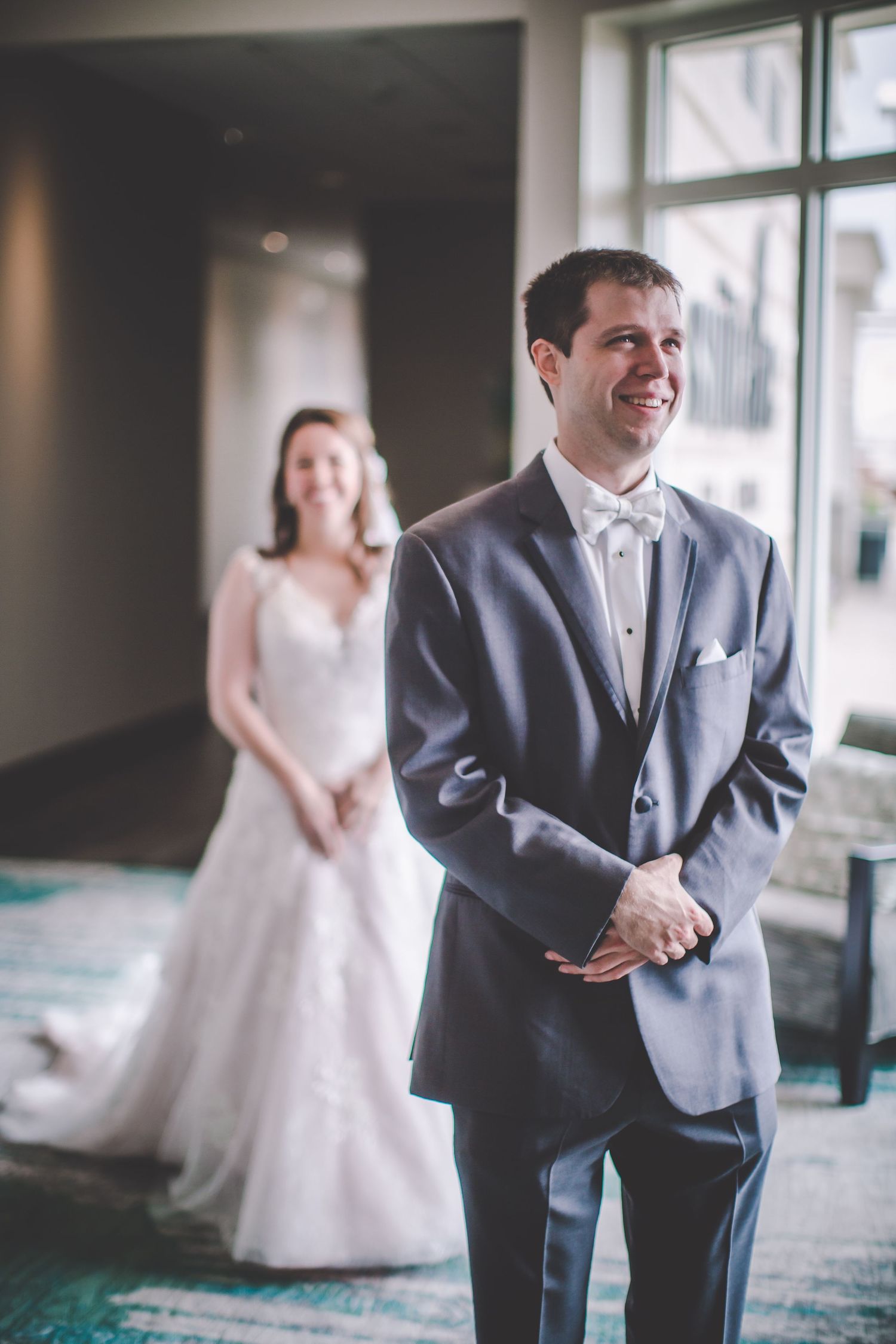 First look wedding moment captured in sequence showing joyful reactions by a window.
