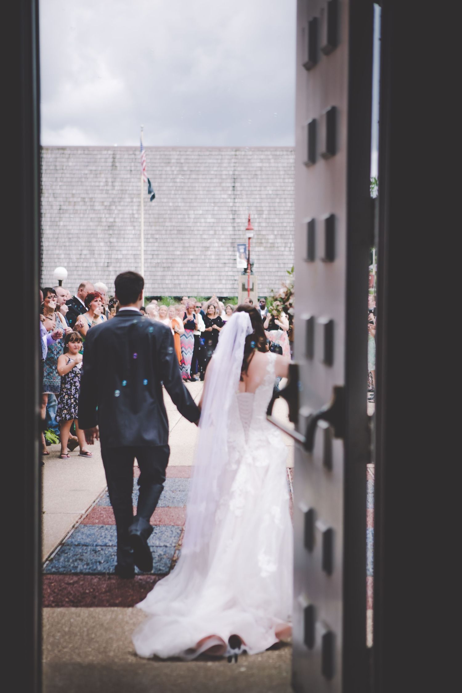 Newlyweds exit through church doors as guests gather outside for the celebration.
