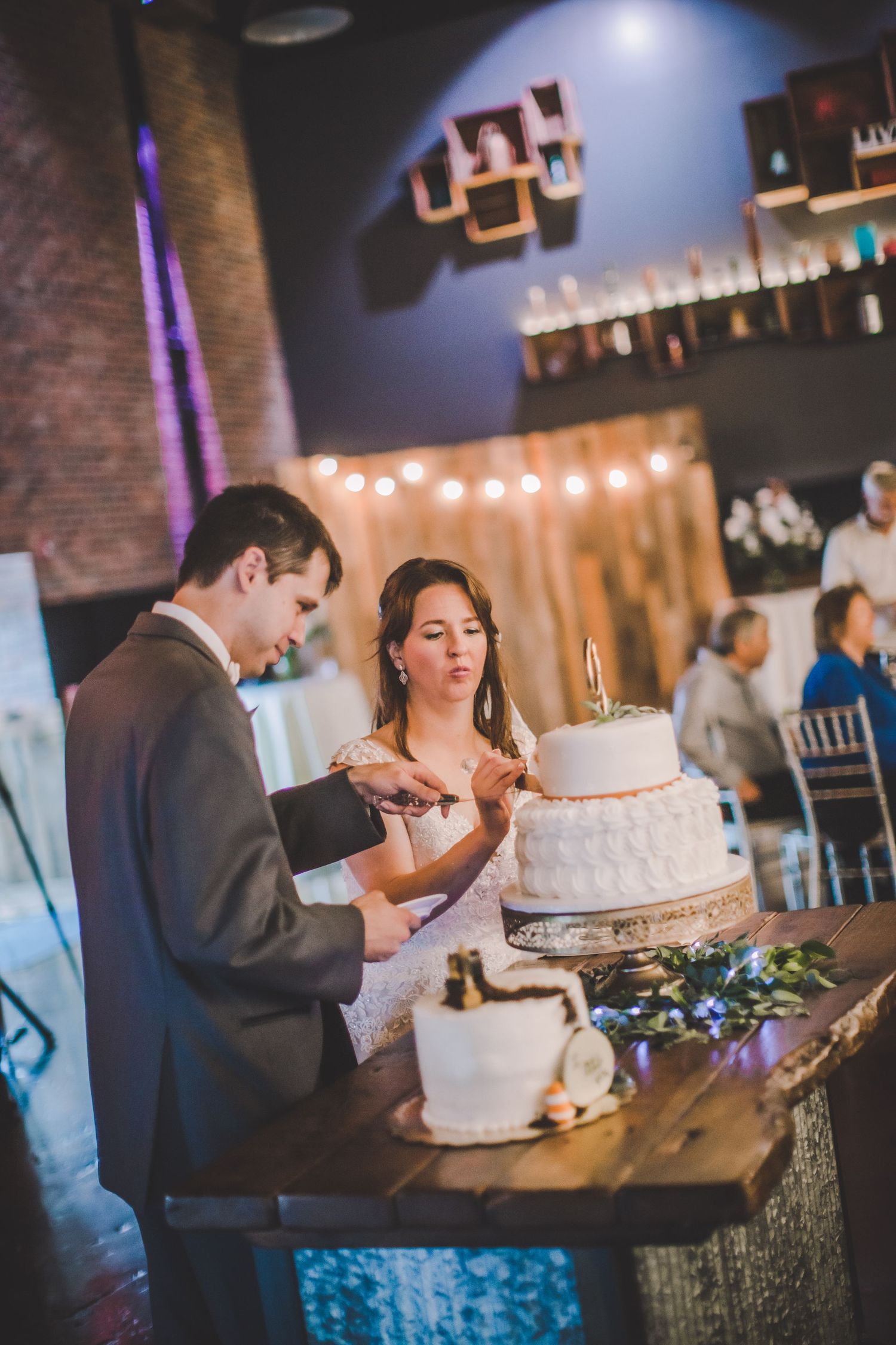 Traditional cake cutting ceremony at wedding reception with ambient lighting and rustic details.