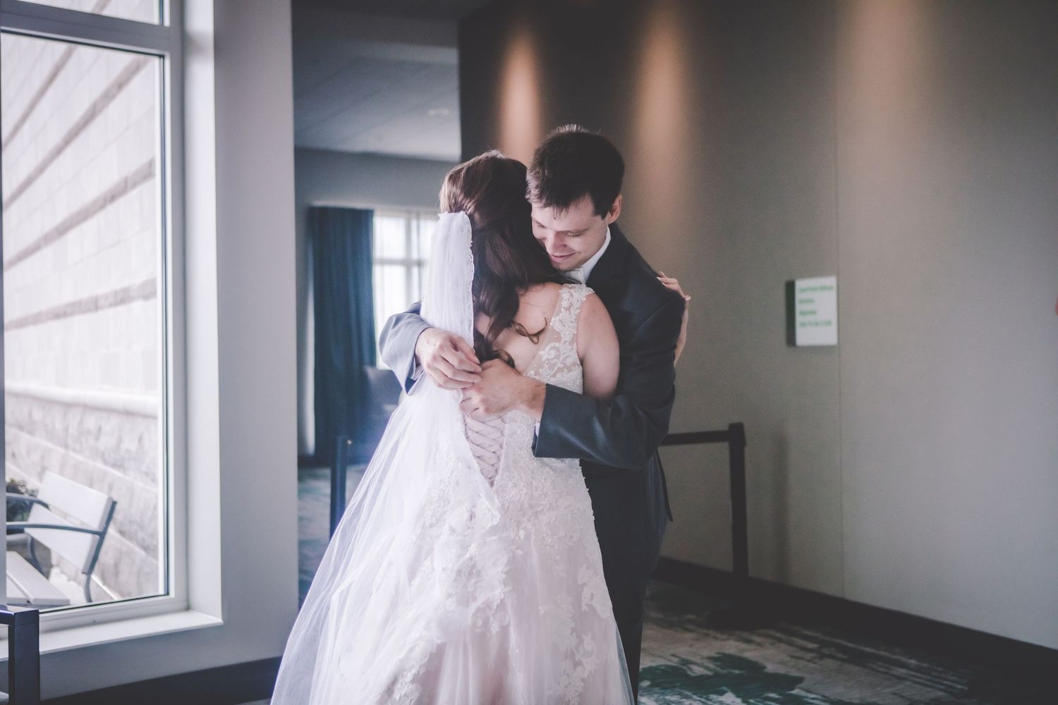 An intimate moment between newlyweds dancing in soft window light.