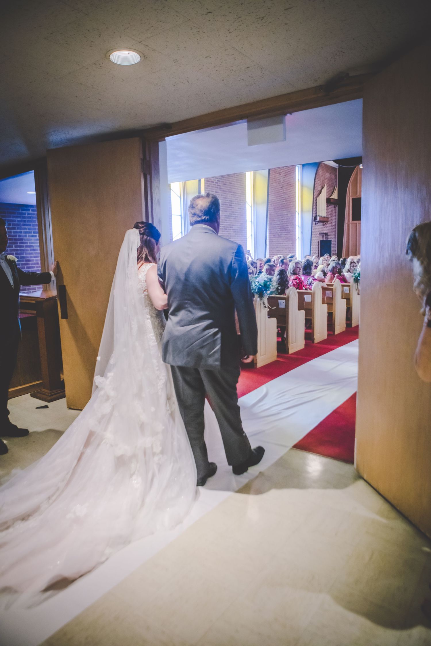A bride and her escort prepare to walk down a church aisle before the wedding ceremony.