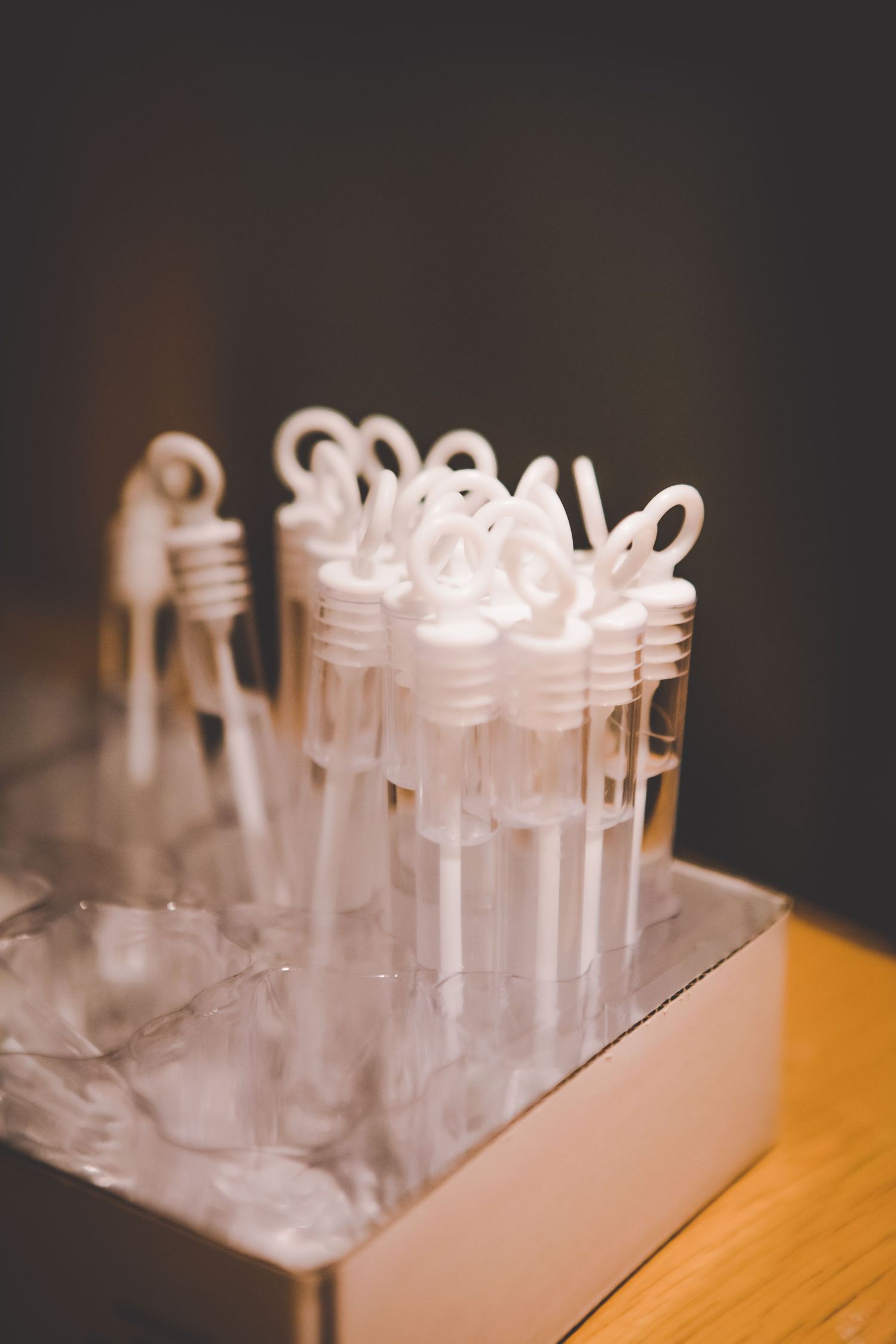 White bubble wands arranged in a decorative display holder for a wedding celebration.