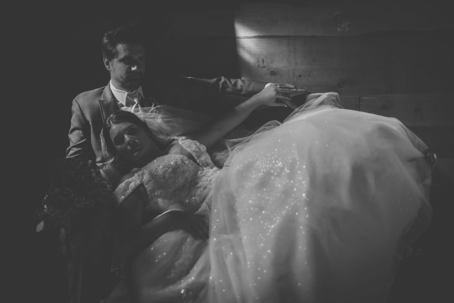Black and white wedding photo capturing intimate moment in rustic setting.