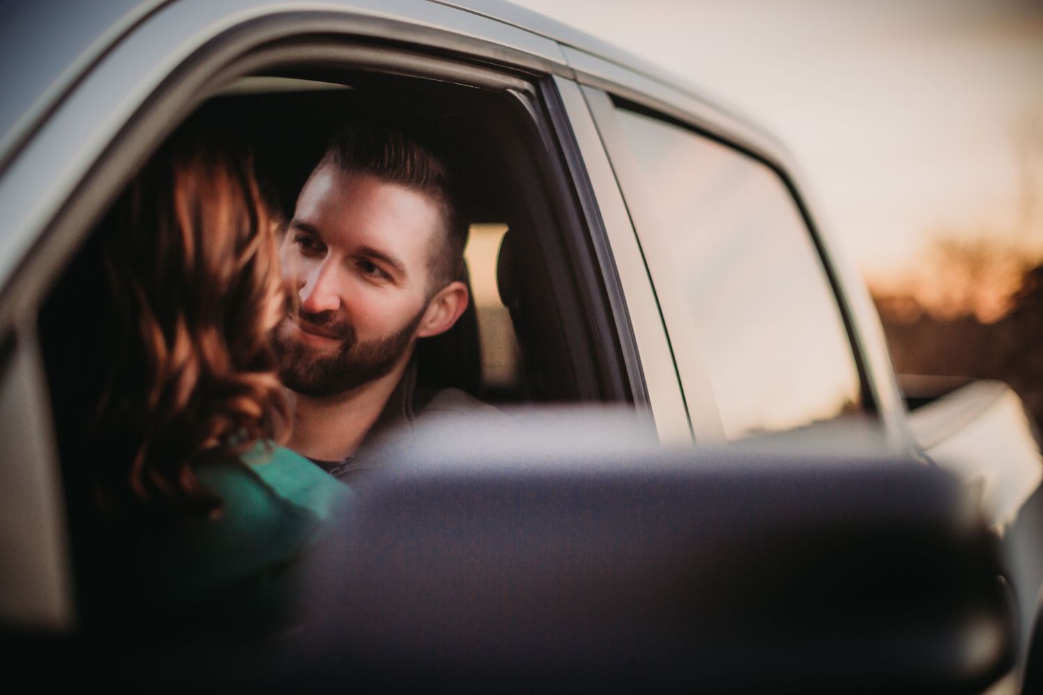 Tender moment captured through car window during golden hour.
