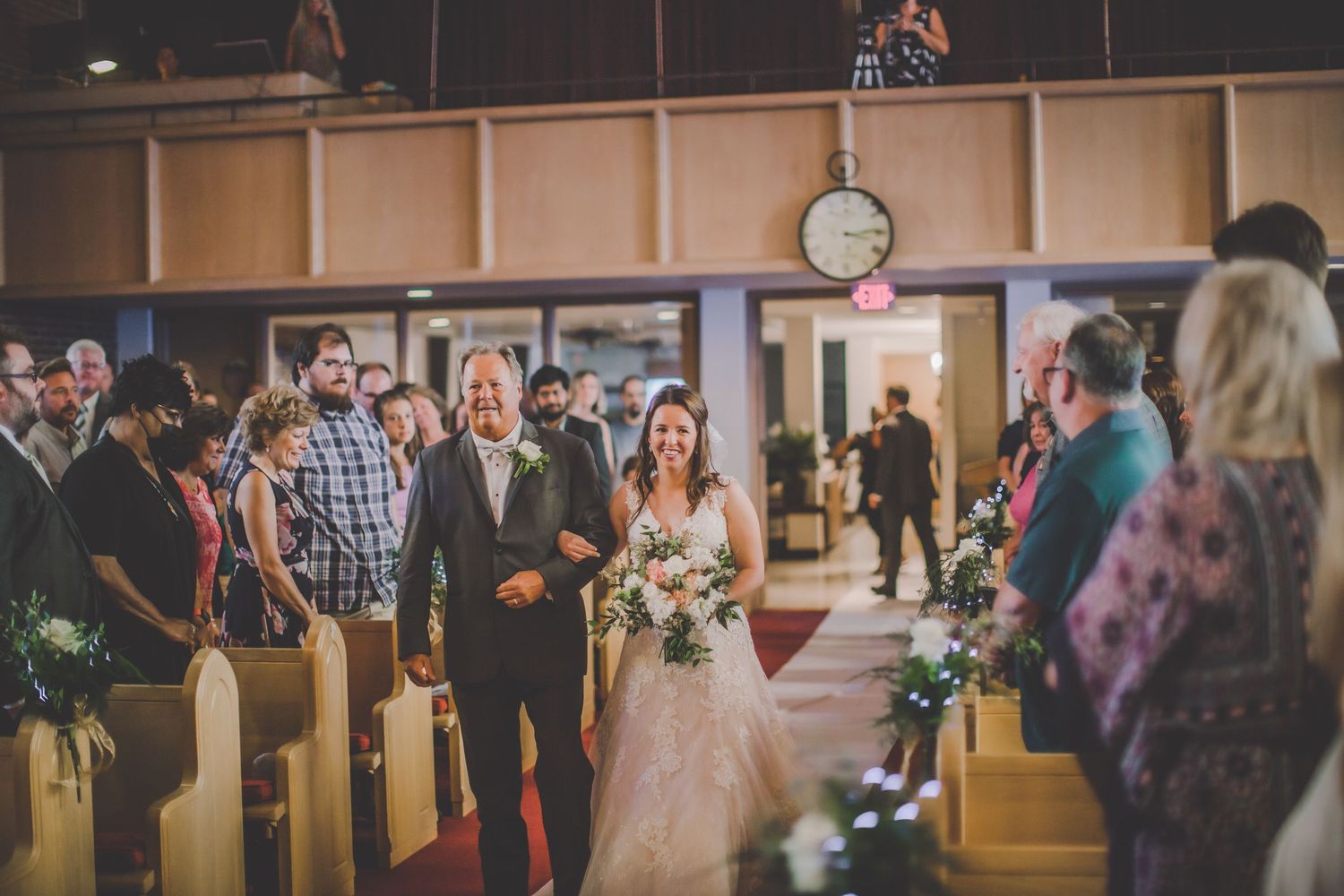 Wedding guests seated in church pews during indoor ceremony.