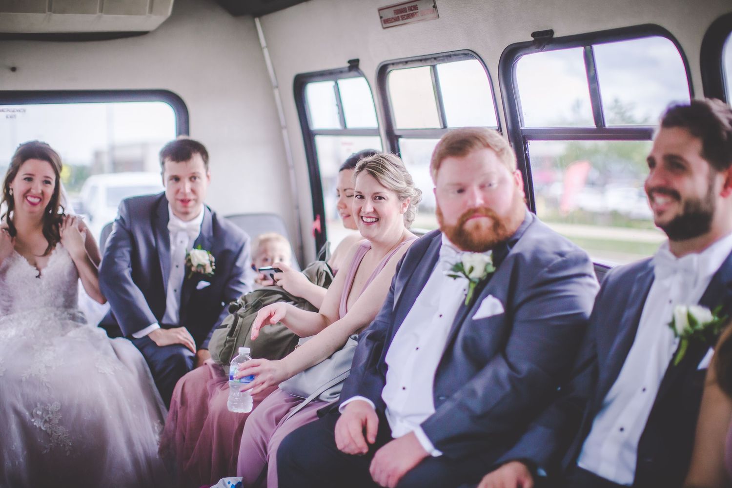 Wedding party laughs together while riding in decorated celebration vehicle.