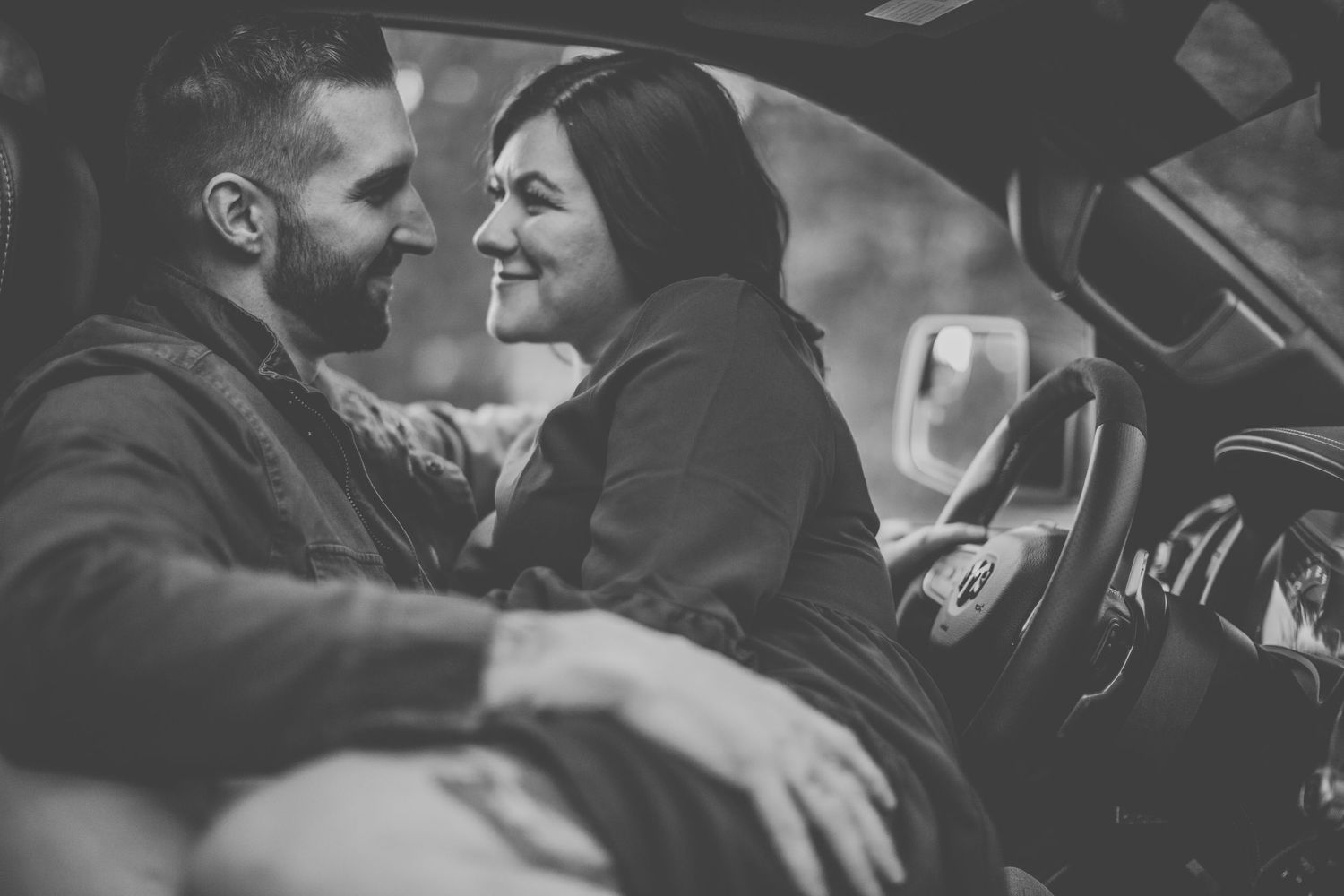 Black and white photo of joyful moment shared in car front seats.