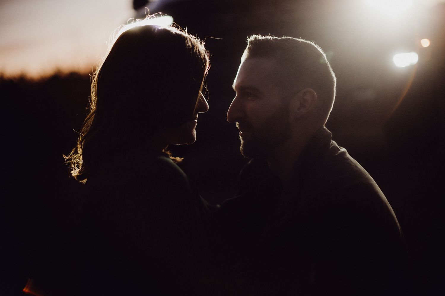 Silhouetted couple in romantic close-up against dramatic lighting.