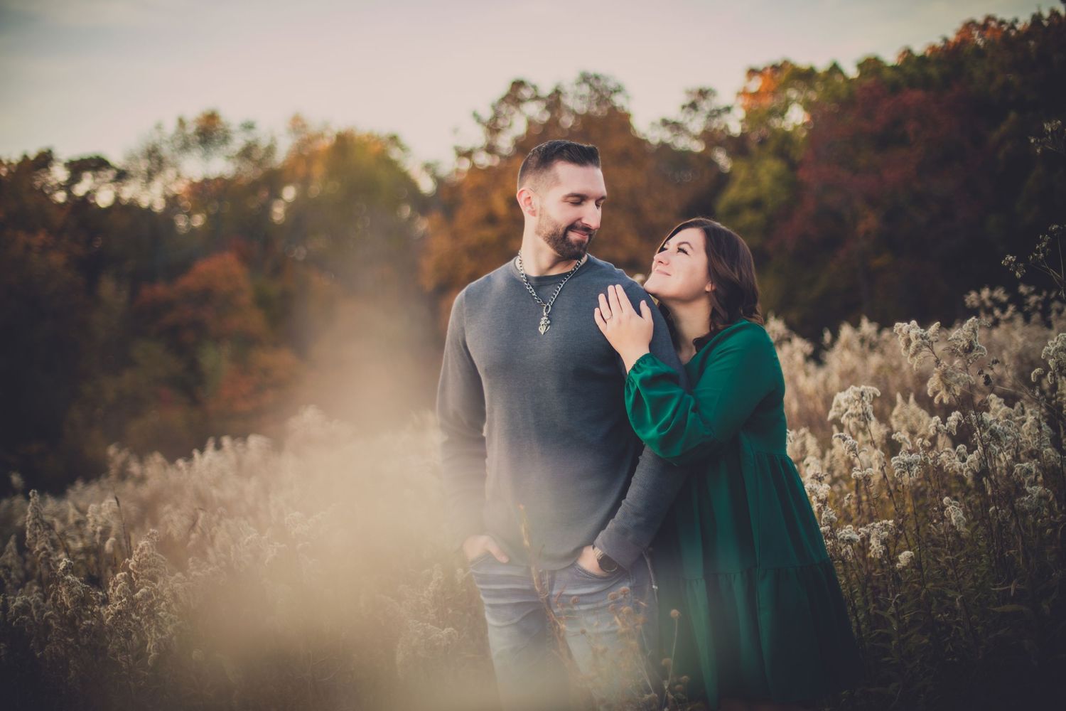 Romantic autumn portrait in field with natural golden light and dried grasses.